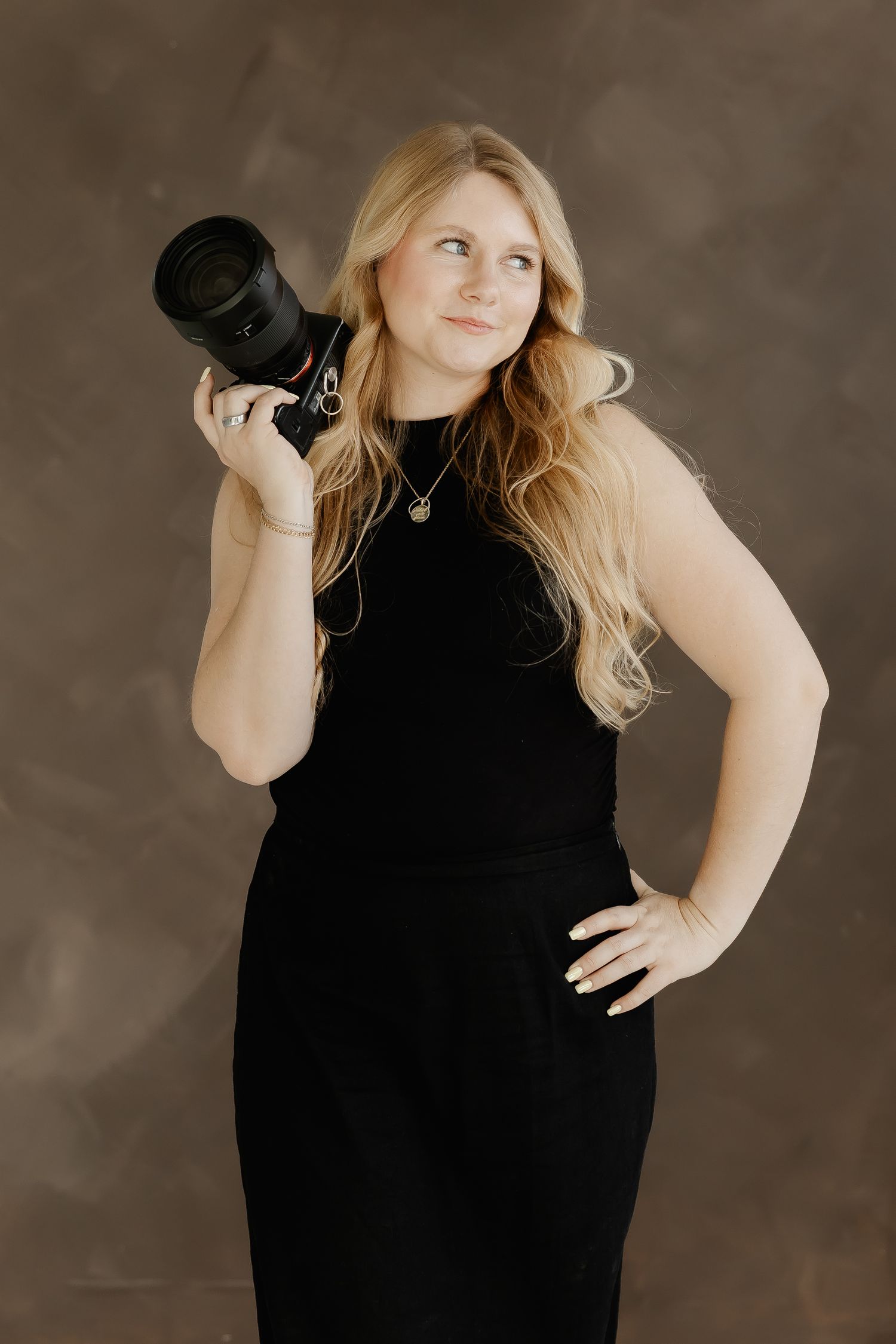 A photo series showing the same person in a black dress holding a camera against a dark brown studio backdrop.