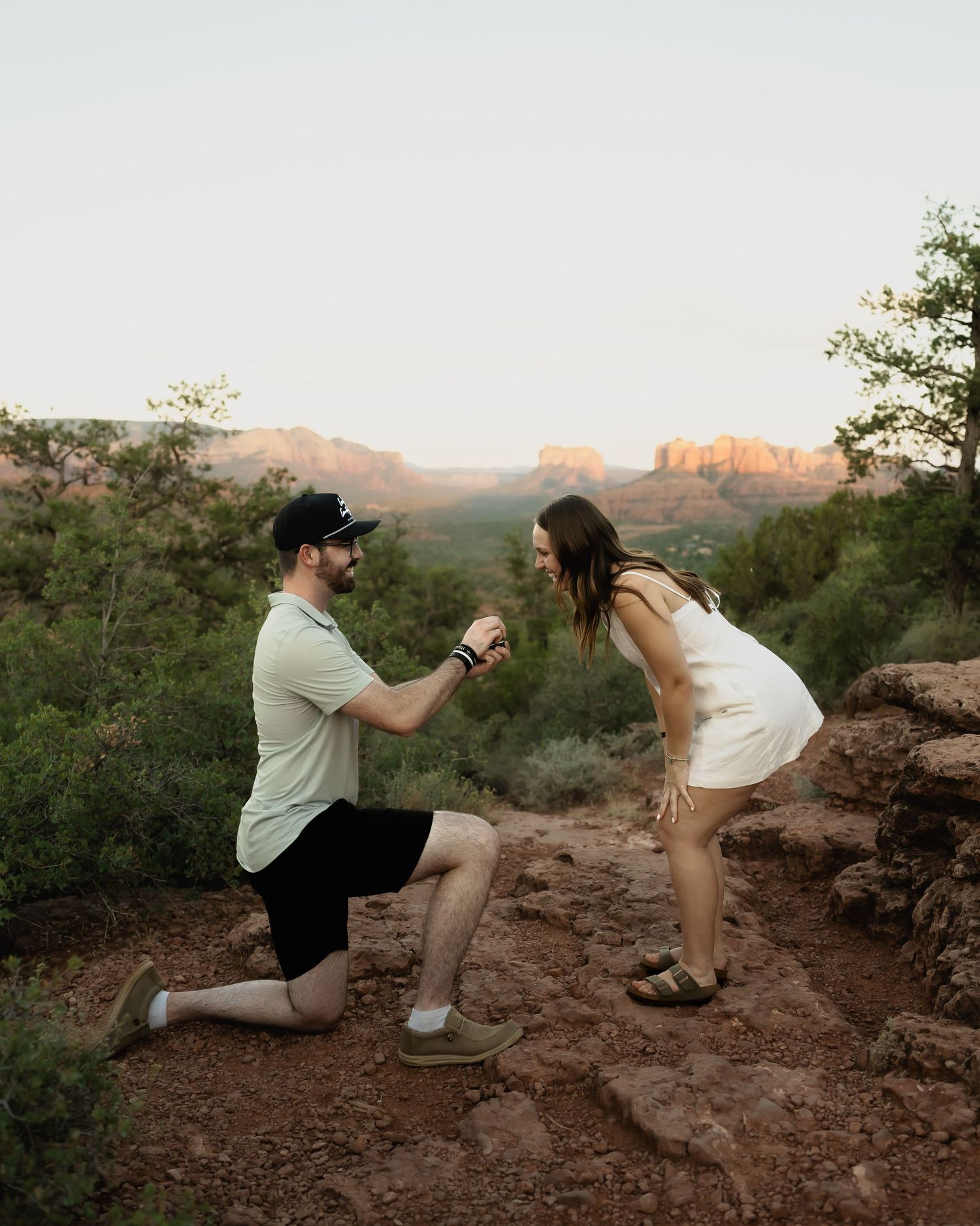 Surprise proposal moment captured on red rocks during golden hour.