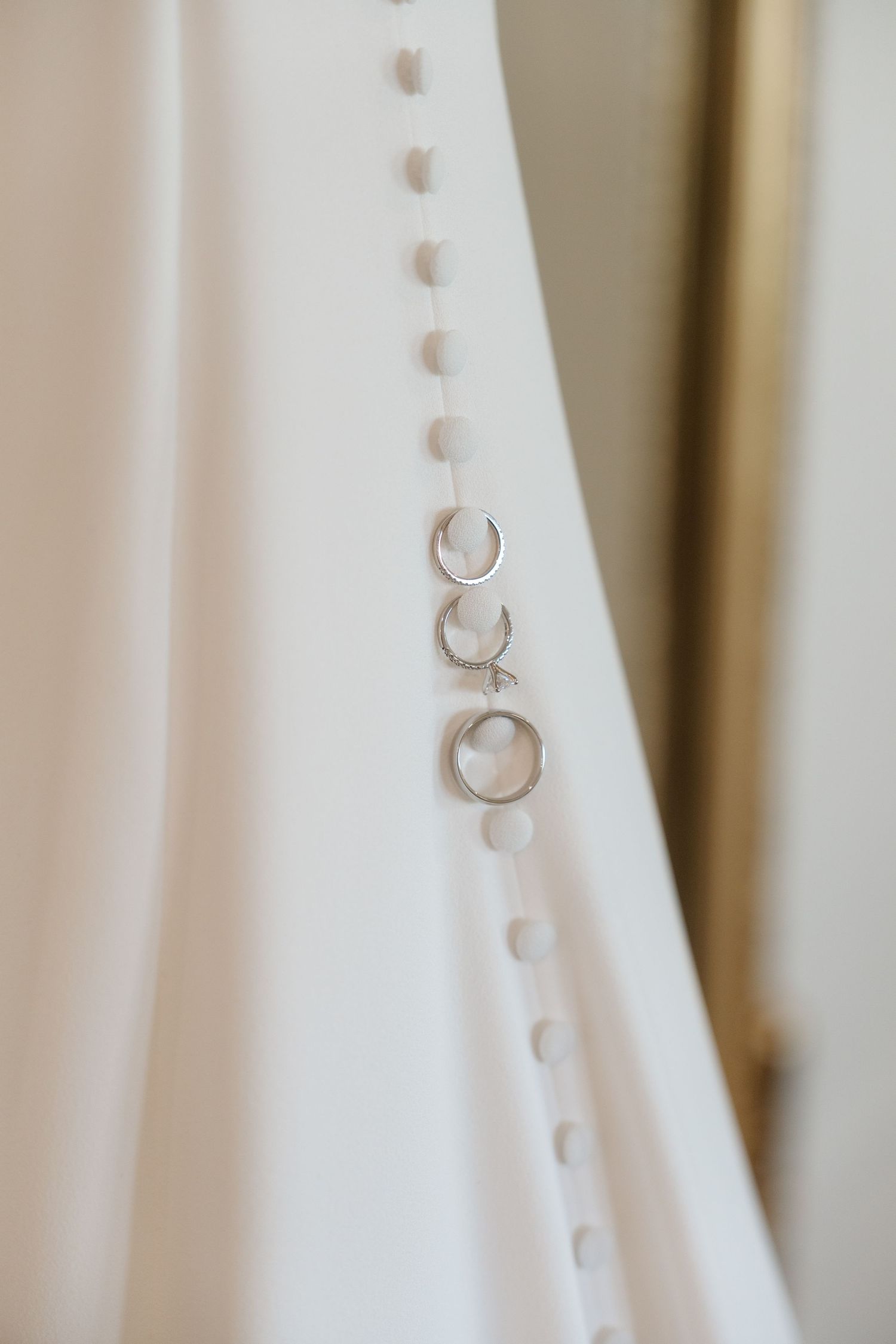 Close-up view of elegant white wedding dress details showing delicate button closures in a row.