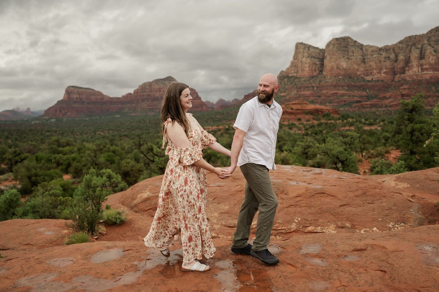 Candid moments captured on red rock formations under cloudy desert skies.