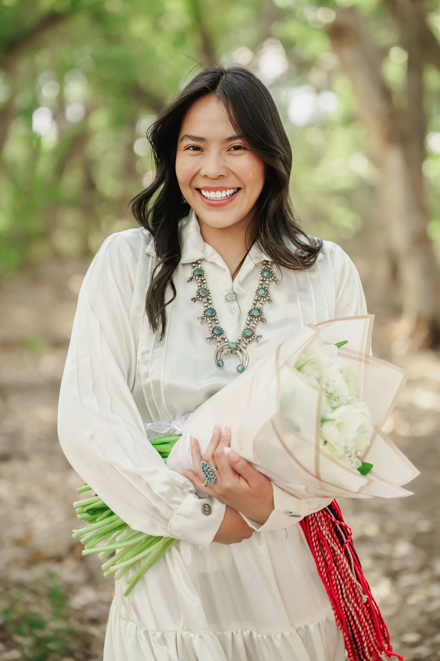 Spring outdoor portrait session with white dress and floral bouquet in natural setting.