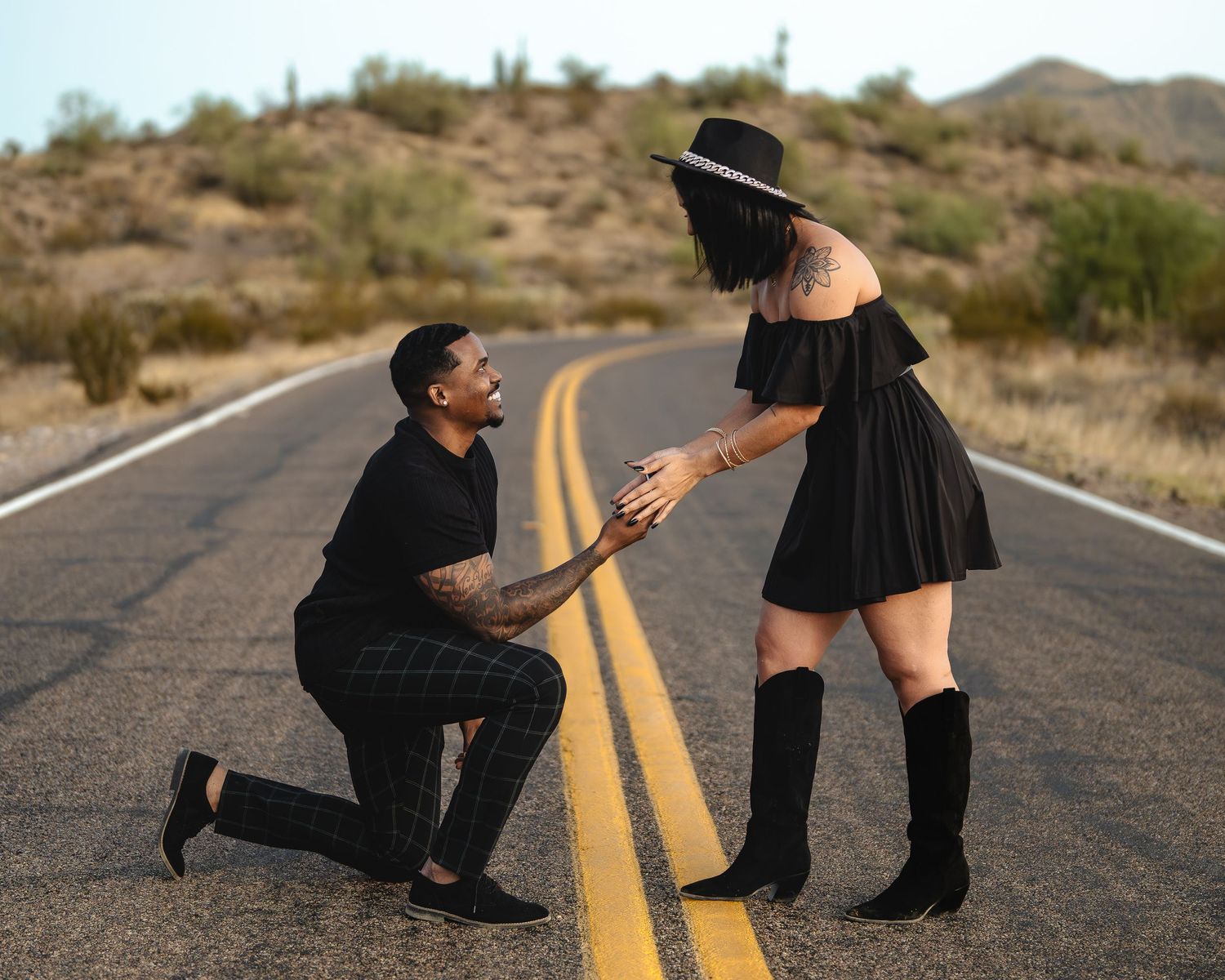 Marriage proposal scene on desert highway with saguaro cacti in background.