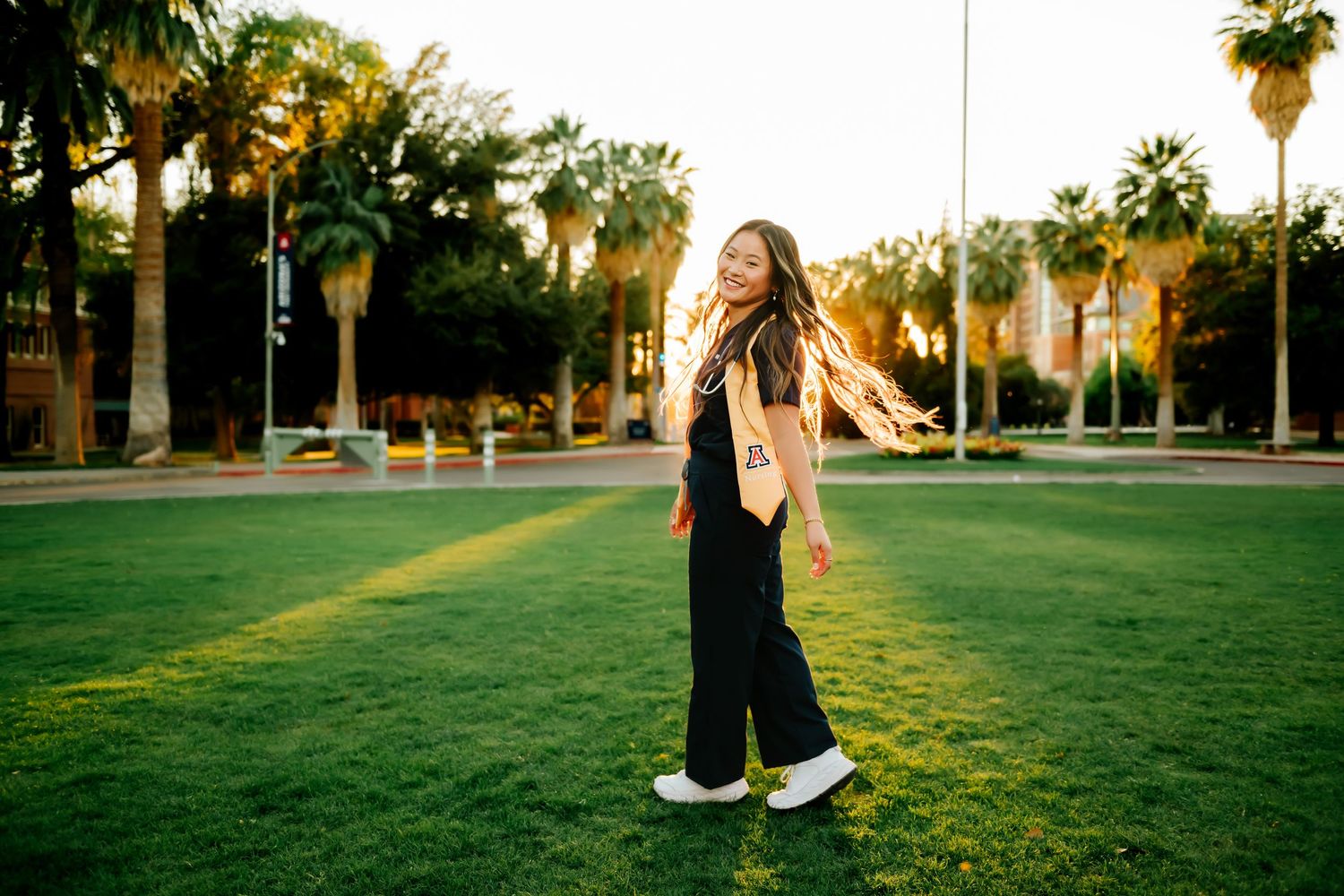 University of Arizona Nursing graduate in front of a green lawn, spinning with long hair.