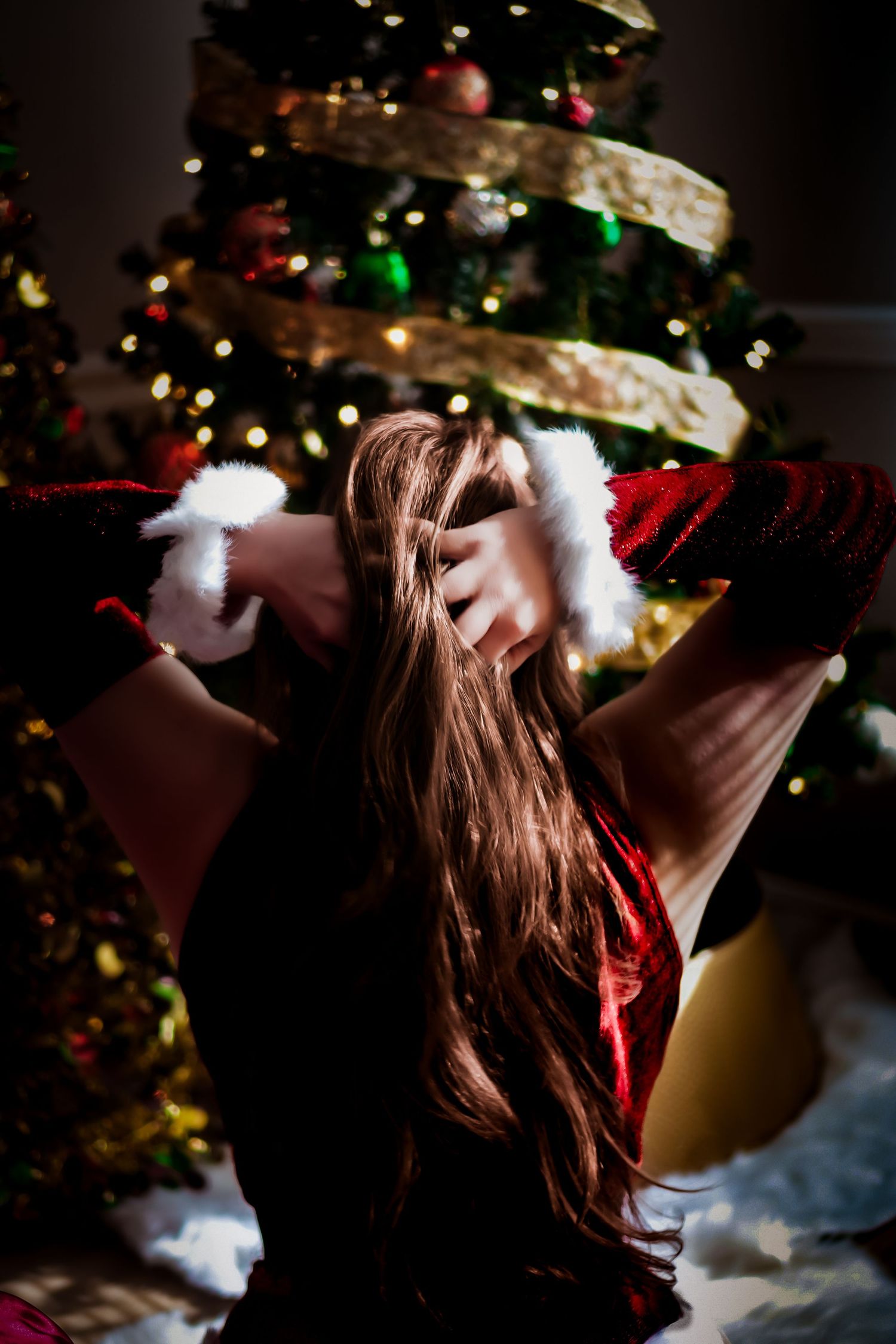 Dark festive photo series with decorated Christmas tree bokeh lights and flowing brown hair against holiday backdrop.