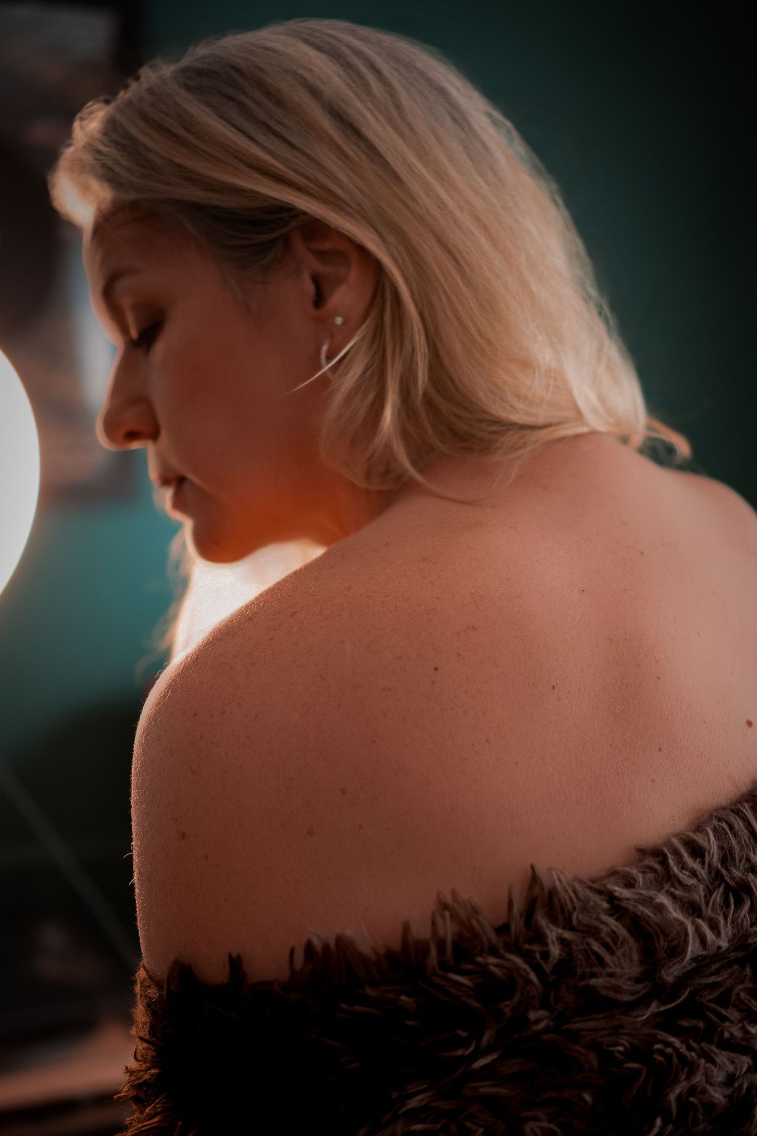 A silhouetted figure in a black feathered dress is illuminated from behind with dramatic lighting.