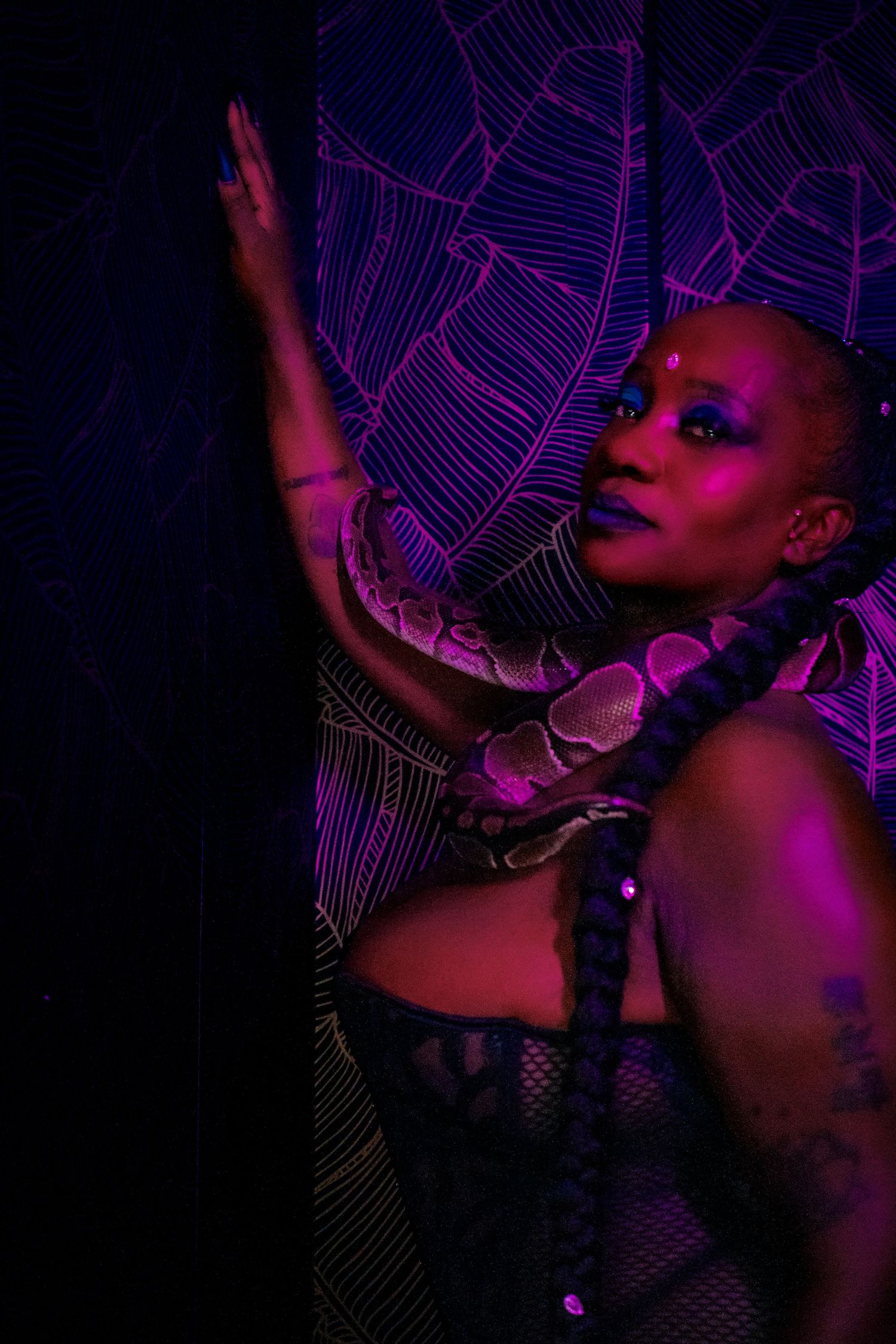 Artistic portrait in pink and purple neon lighting against a geometric line pattern background in dark setting.