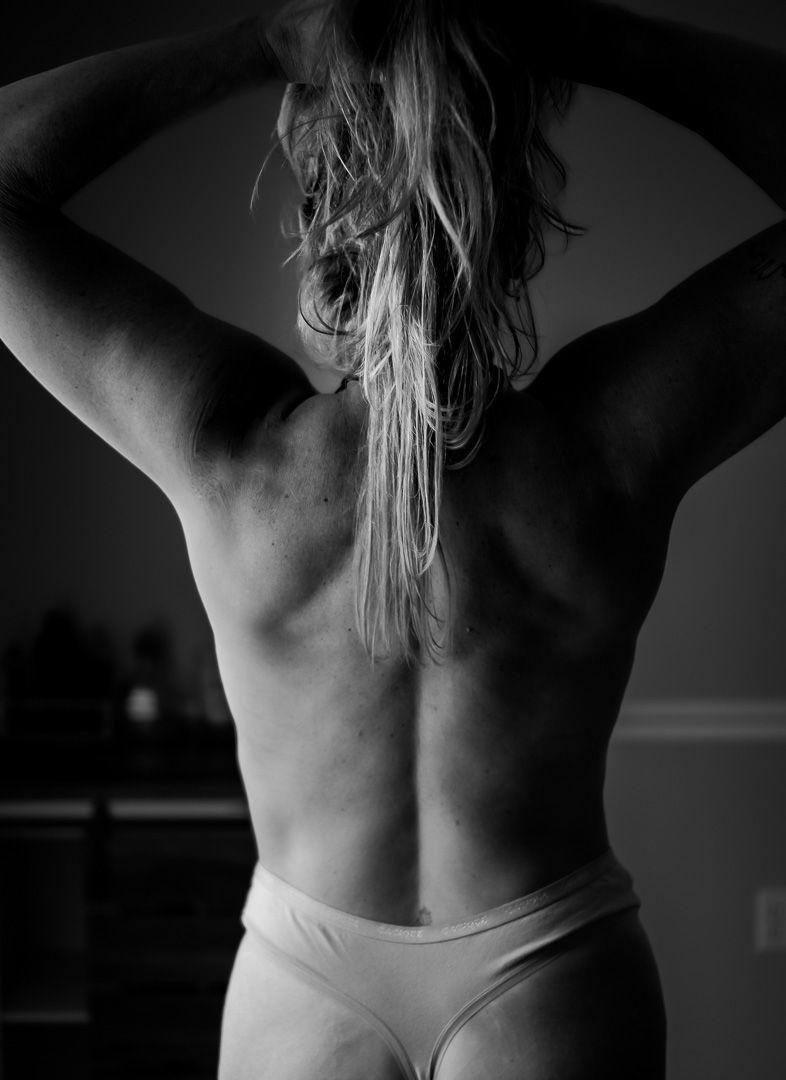 Black and white artistic photographs showing bare back views of a person stretching and posing against dark background.