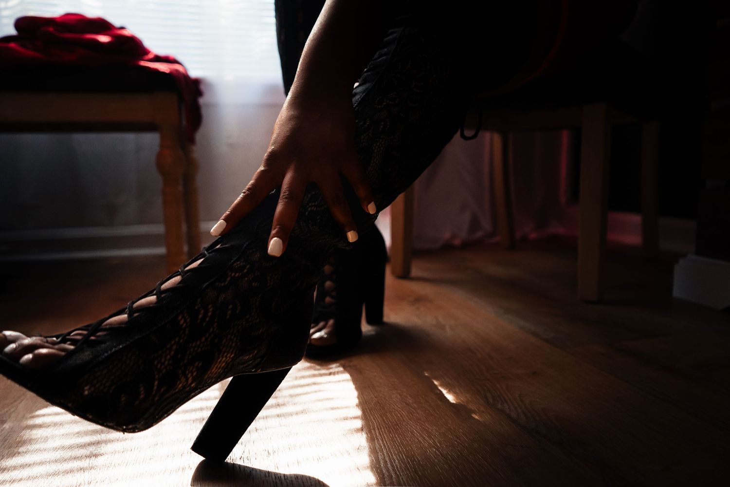 A dancer's feet in dark clothing leap gracefully across a wooden floor illuminated by dramatic lighting.