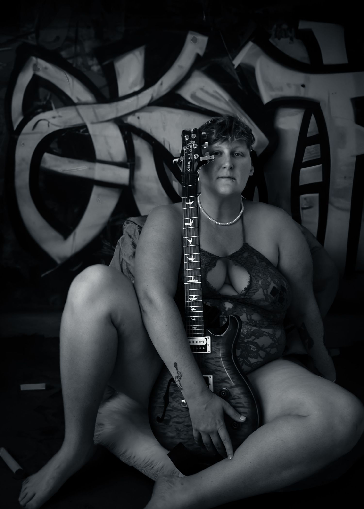 Black and white artistic boudoir photography series showing intimate poses against graffiti wall backdrop in low light.