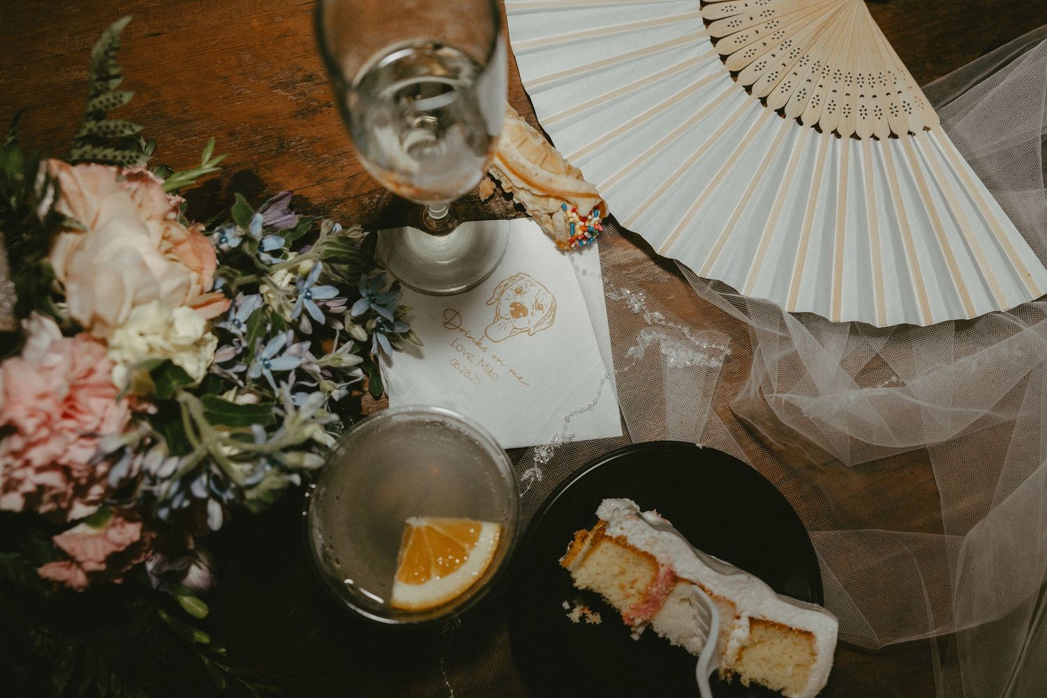 White paper parasols and floral arrangements create an elegant wedding reception backdrop against a rustic wooden wall.