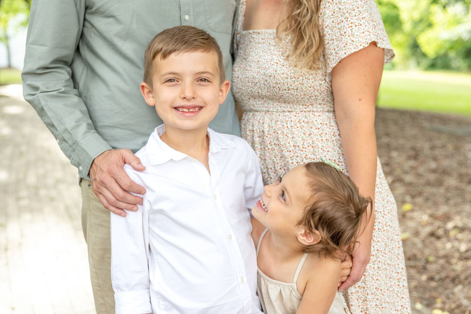 Family wearing coordinated cream and blue outfits poses together outdoors in a natural setting.