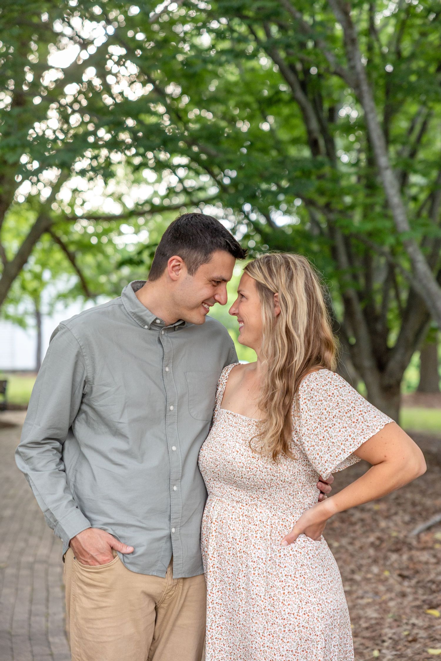 A couple shares romantic moments in a series of four photos taken outdoors under green trees.