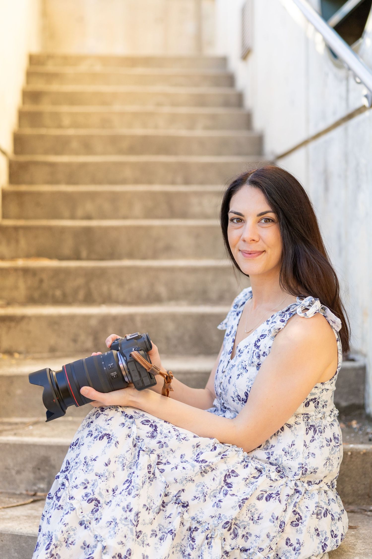 Jessie Peloso Photography - a family photographer in Raleigh NC sits on the stairs with her camera.