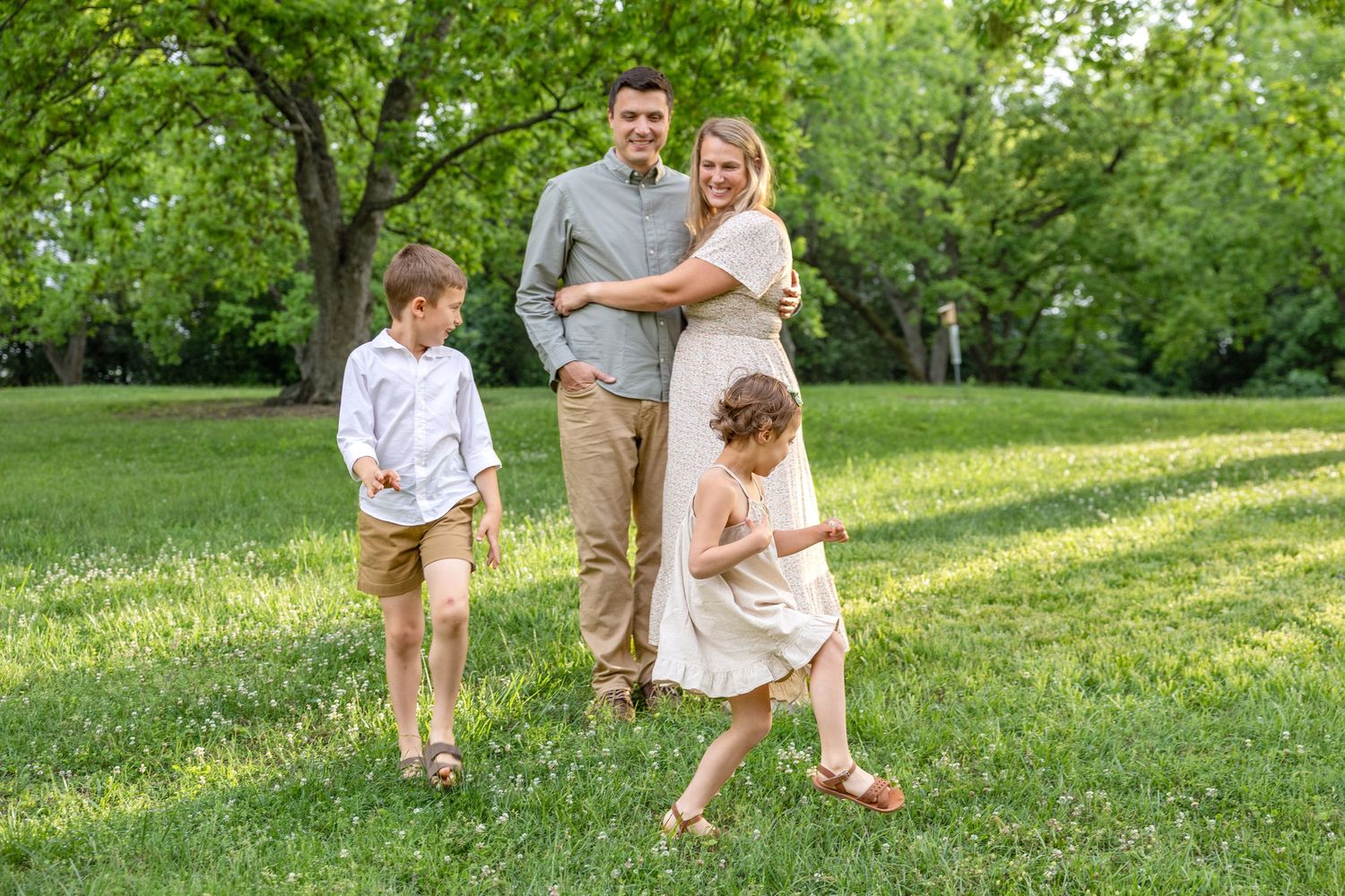 A family enjoying a sunny afternoon together in a lush green park setting during golden hour.