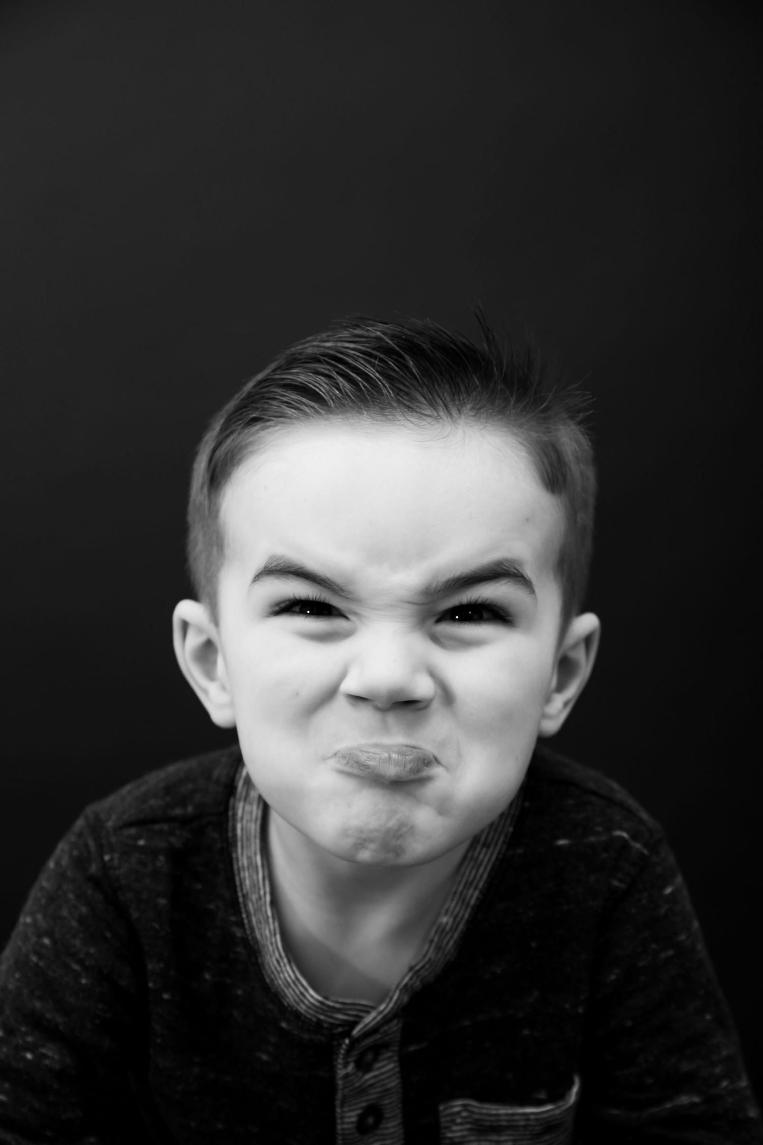 Dramatic black and white portrait showing exaggerated scrunched face expression.