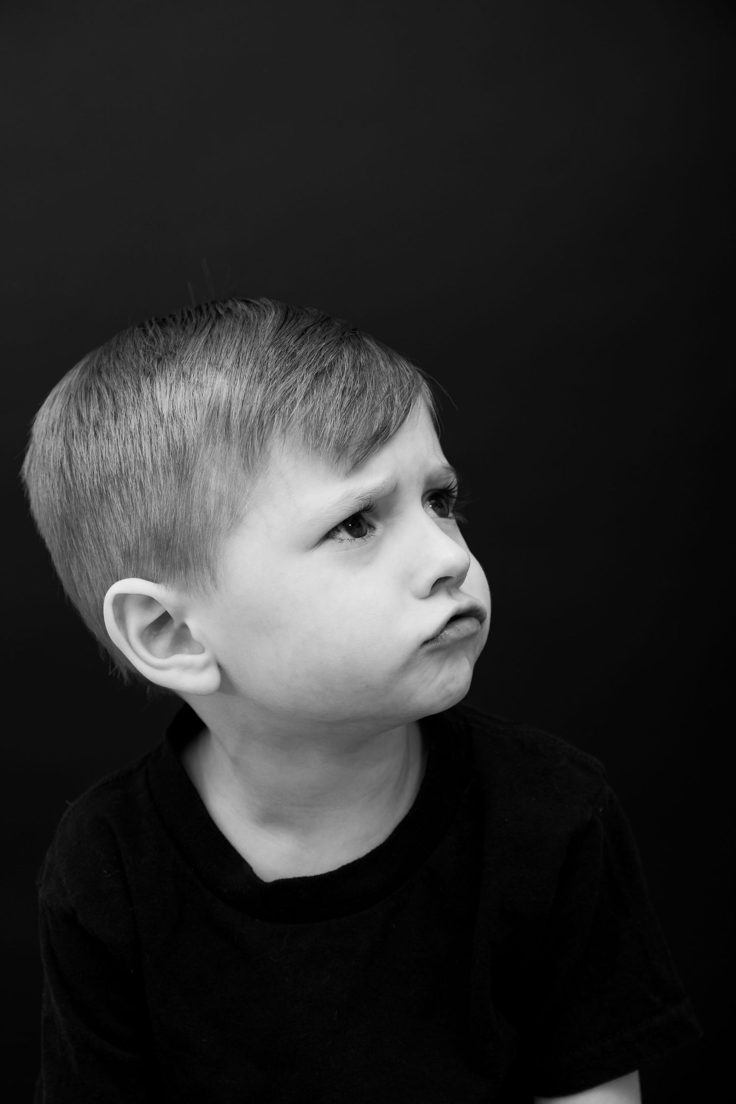 Black and white dramatic portrait showing contemplative side glance.