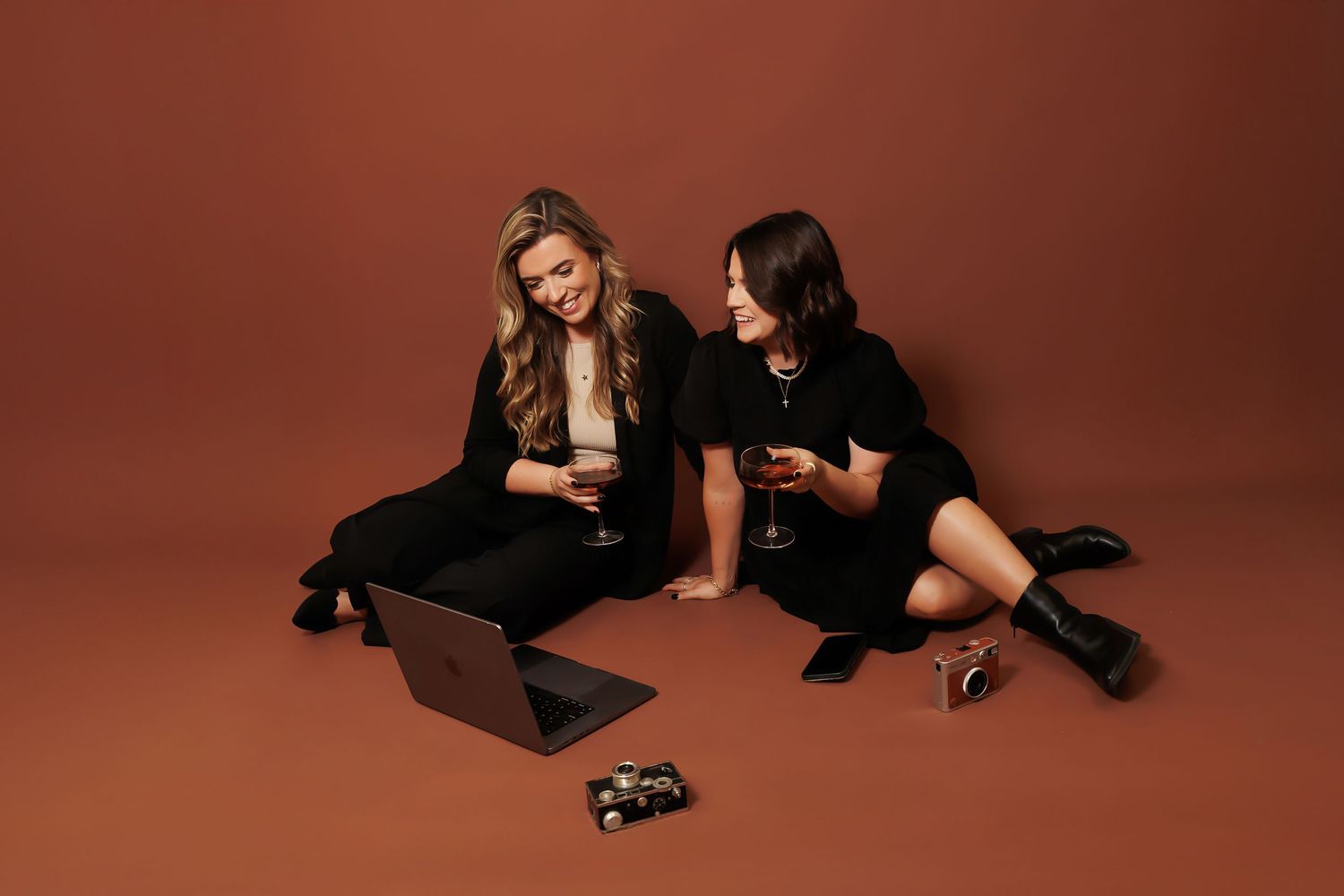 Two people in black clothing pose artistically in various positions against a dark brown backdrop.