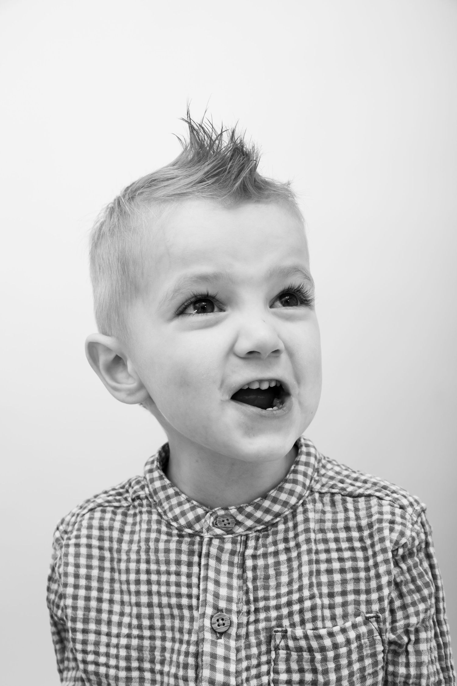 Black and white portrait showing excited expression wearing checkered button-up shirt.