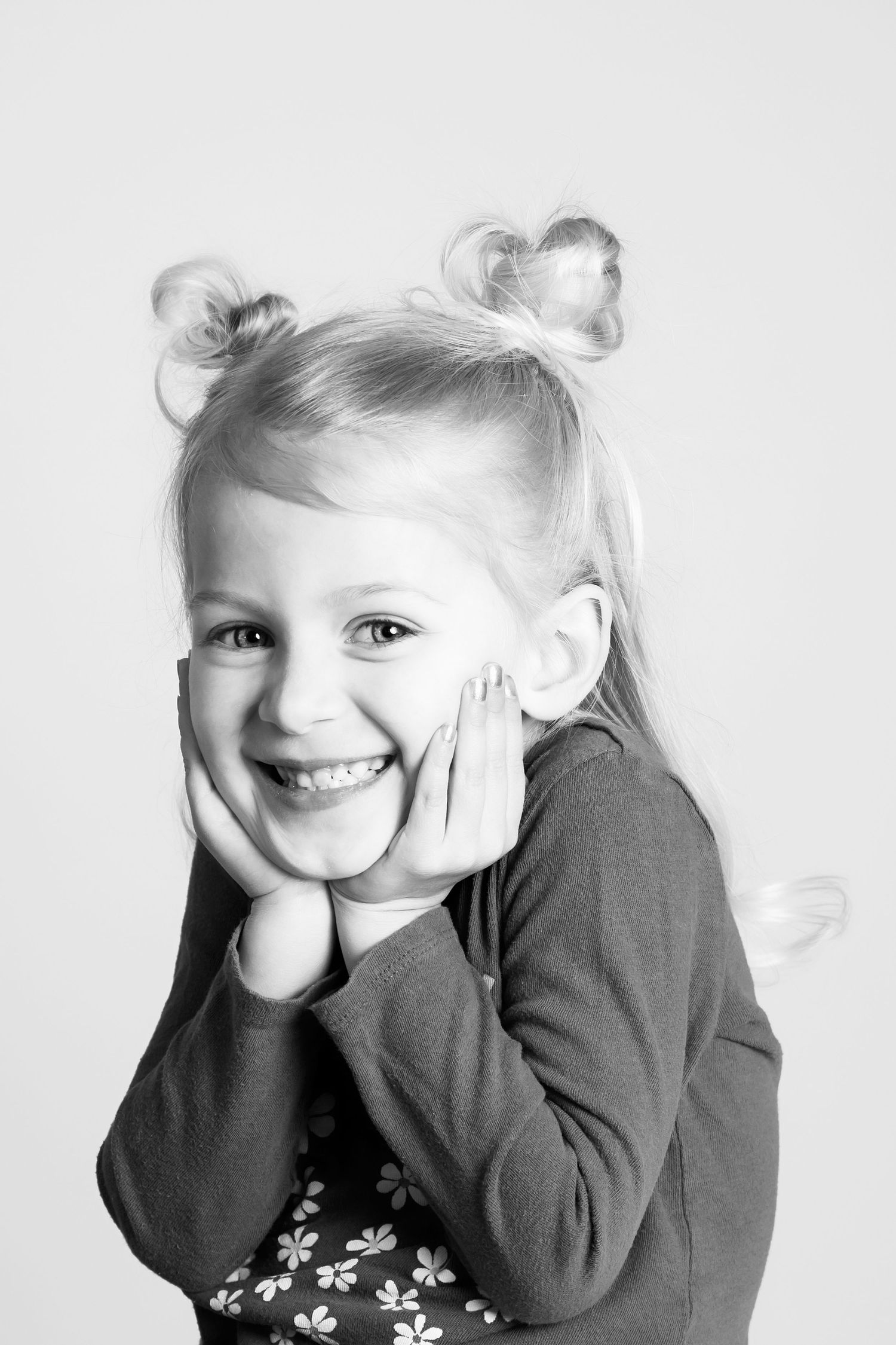 Black and white portrait showing bright smile with hands framing face.