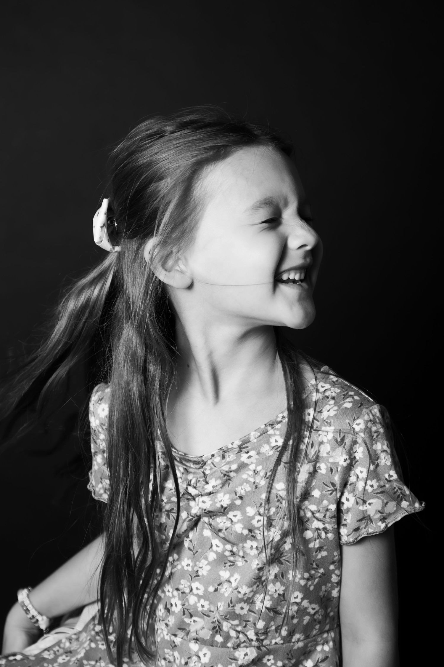 Black and white portrait of joyful girl in floral dress.