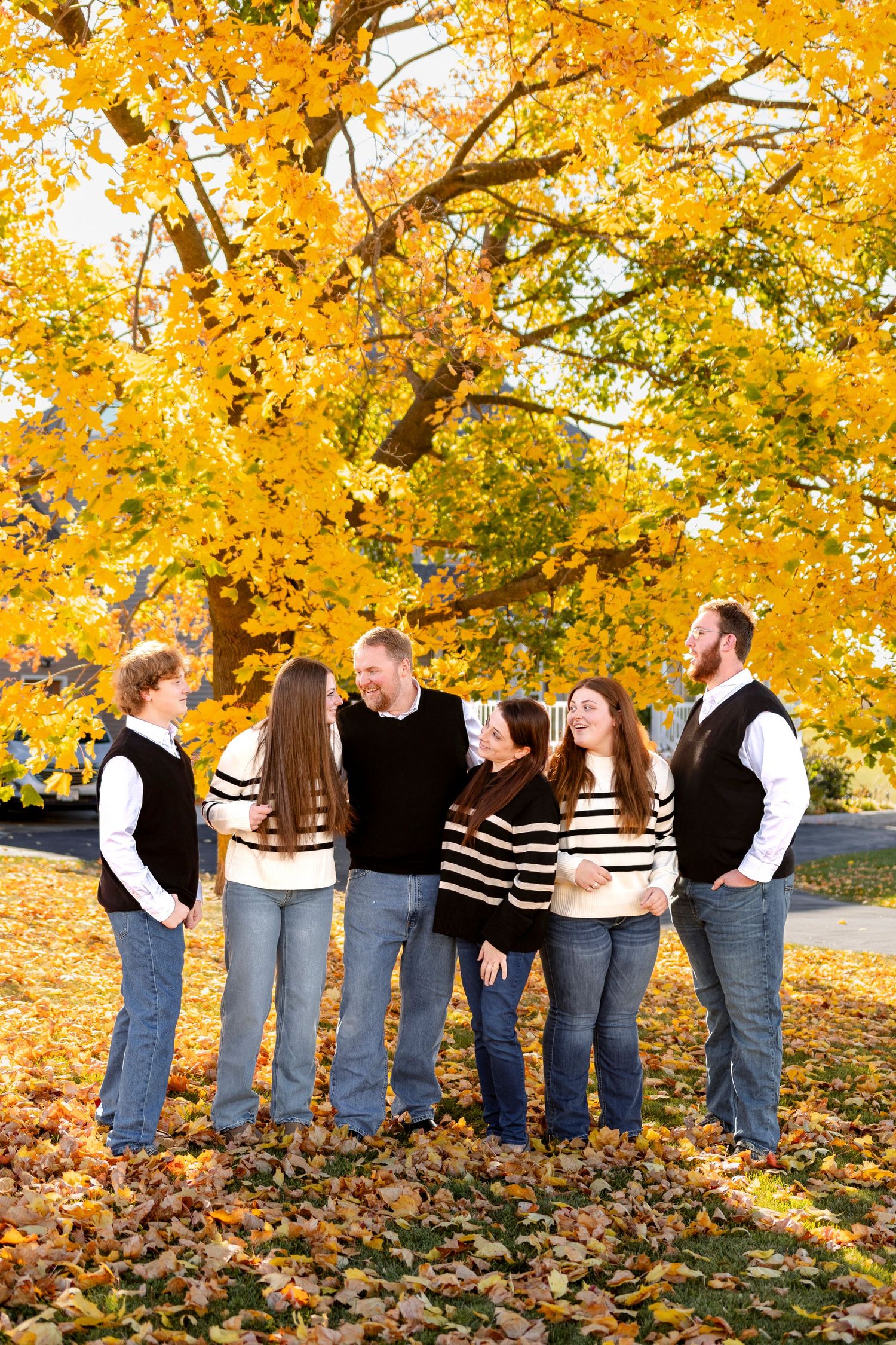 A group stands together under vibrant yellow fall foliage with matching black and white striped outfits.