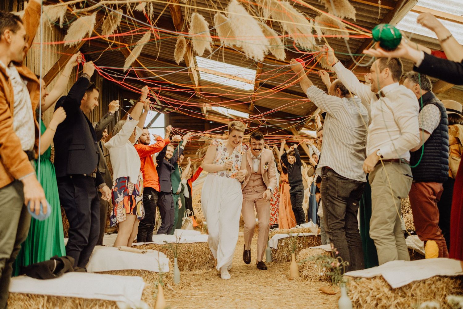 Wedding guests celebrate by waving white napkins during a joyful reception in a rustic wooden venue.