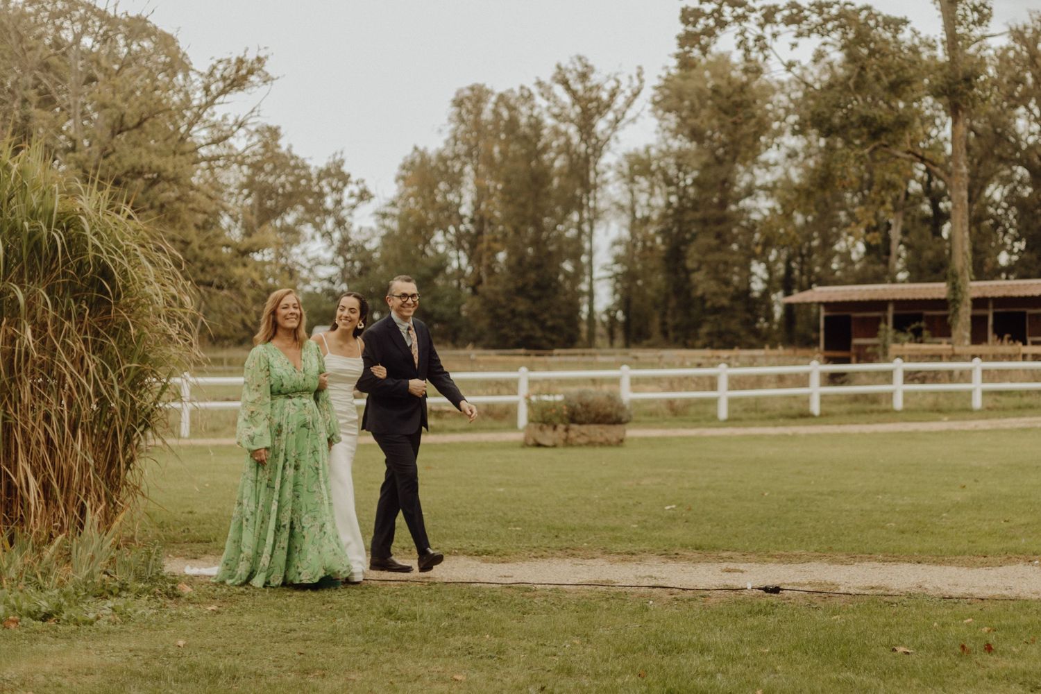 A couple walks together on a grassy field during a golden hour photoshoot at an outdoor venue.