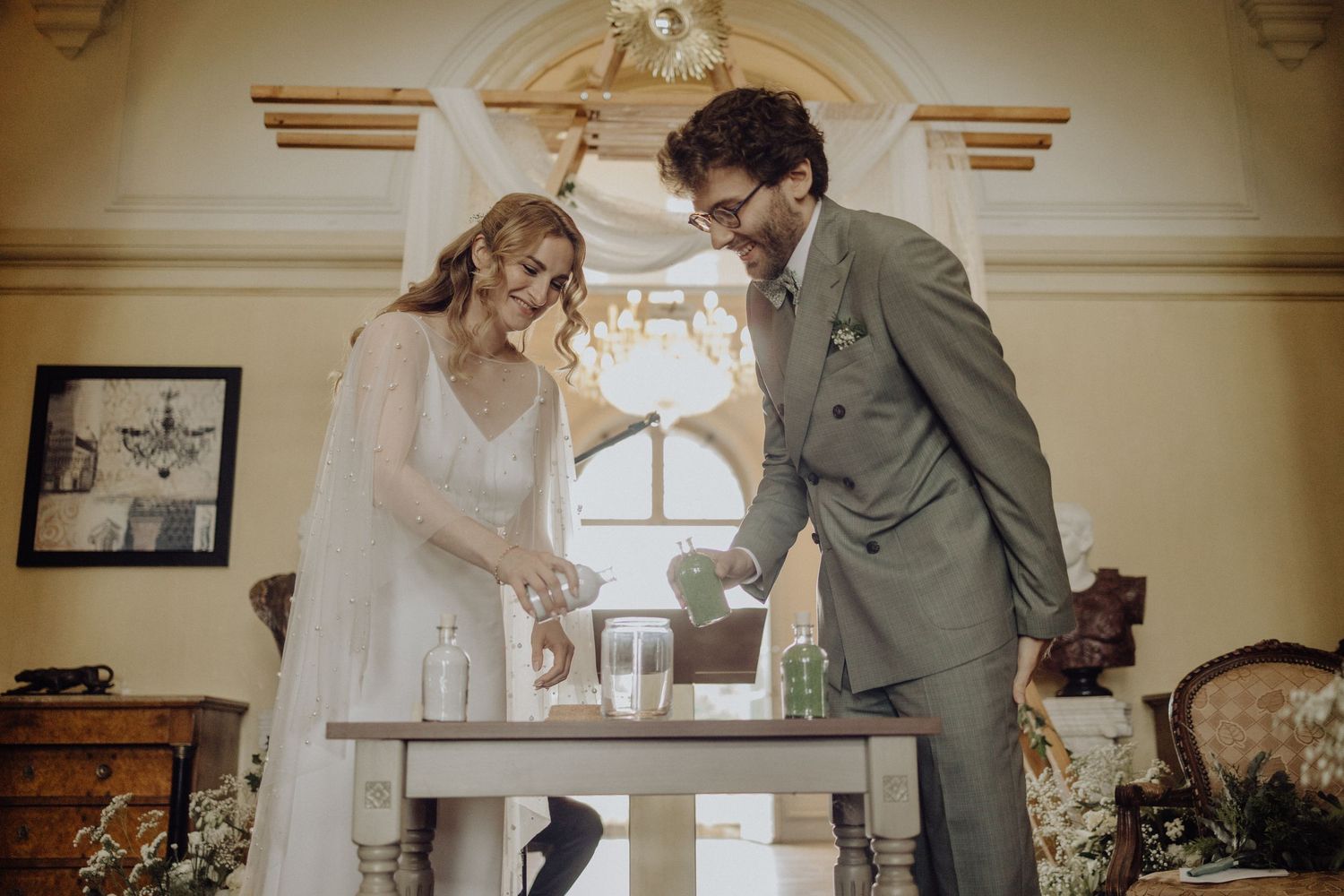 Bride and groom share an intimate moment during their first look in an elegant cream-colored room.