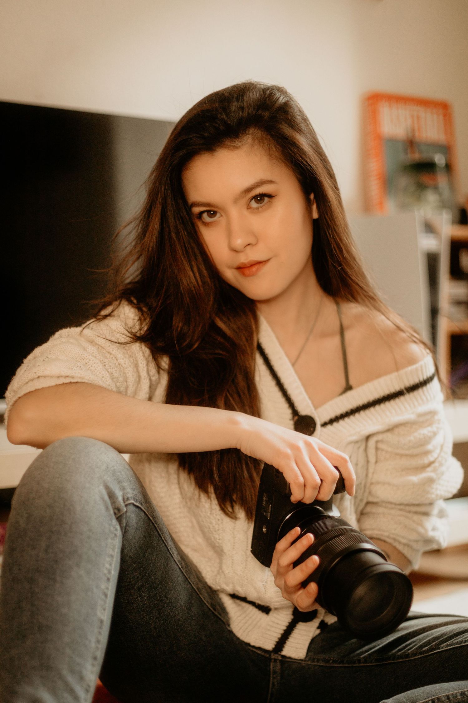 Celala, photographe mariage Clermont-Ferrand Auvergne Rhône-Alpes, en portrait complice avec appareil photo vintage et pull crème.