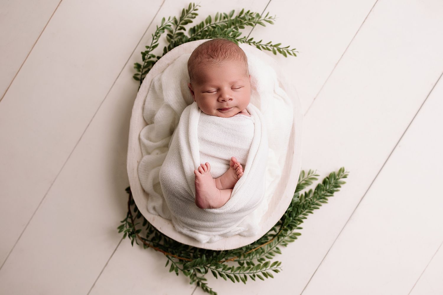 baby boy in white wood bowl encircled in green leafy branches in kansas city metro area studio located Raytown, MO