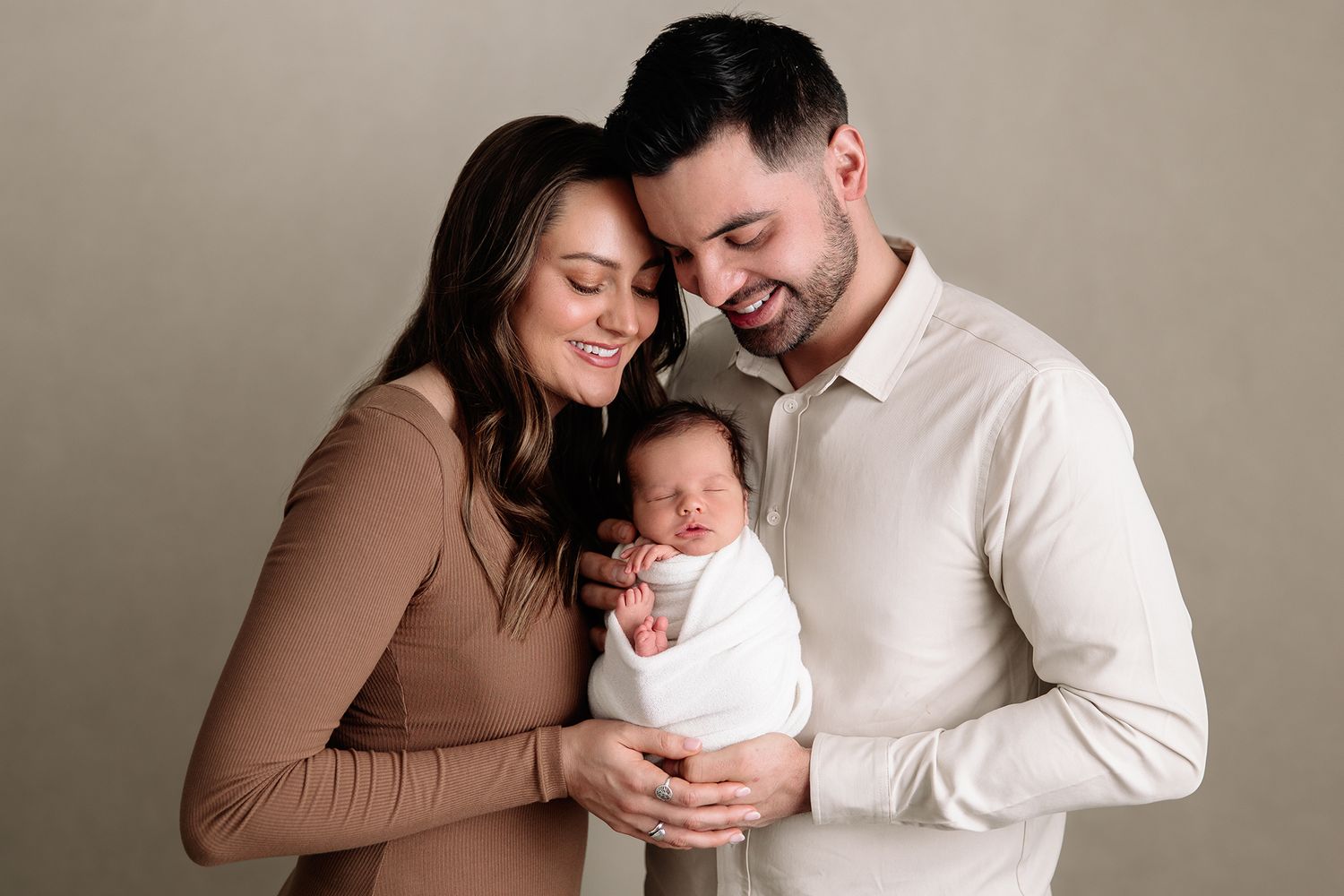 mom and dad hold infant baby boy for first family photo in portrait studio