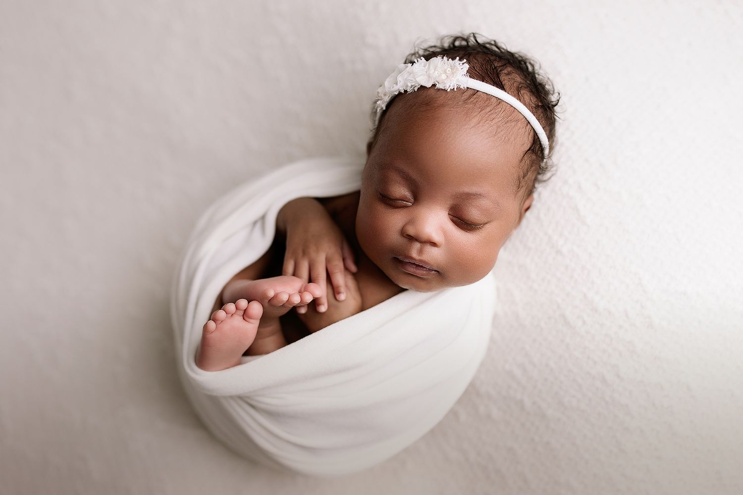 Kansas City newborn photographer. Professional studio session for newborns. baby girl sleeping wrapped in white swaddle.