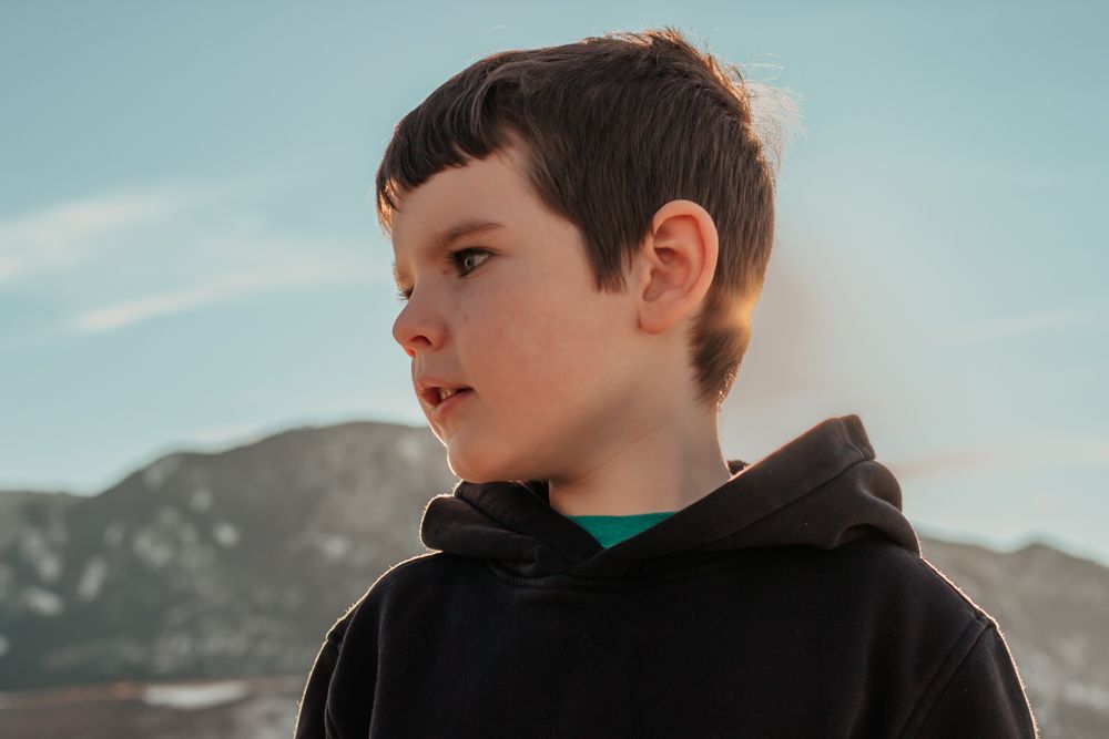 A person gazes thoughtfully at a scenic mountain landscape against a blue sky | | Westminster, CO motherhood & family photographer