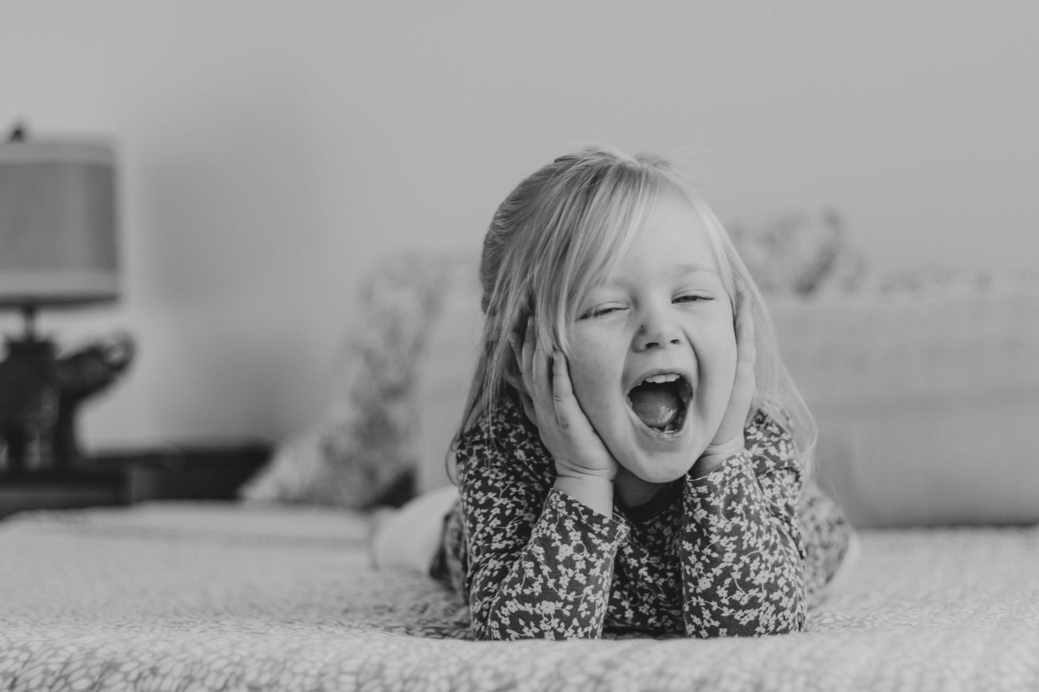 Black and white series showing joyful expressions and laughter on a bed.