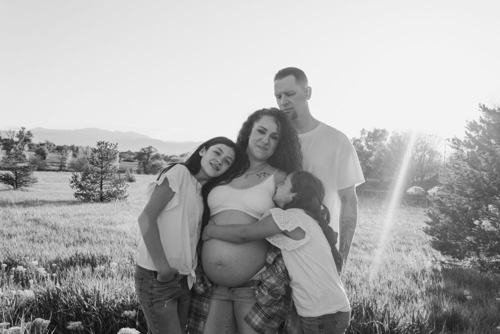 A group poses together outdoors with sun flare creating a dreamy backlit effect.