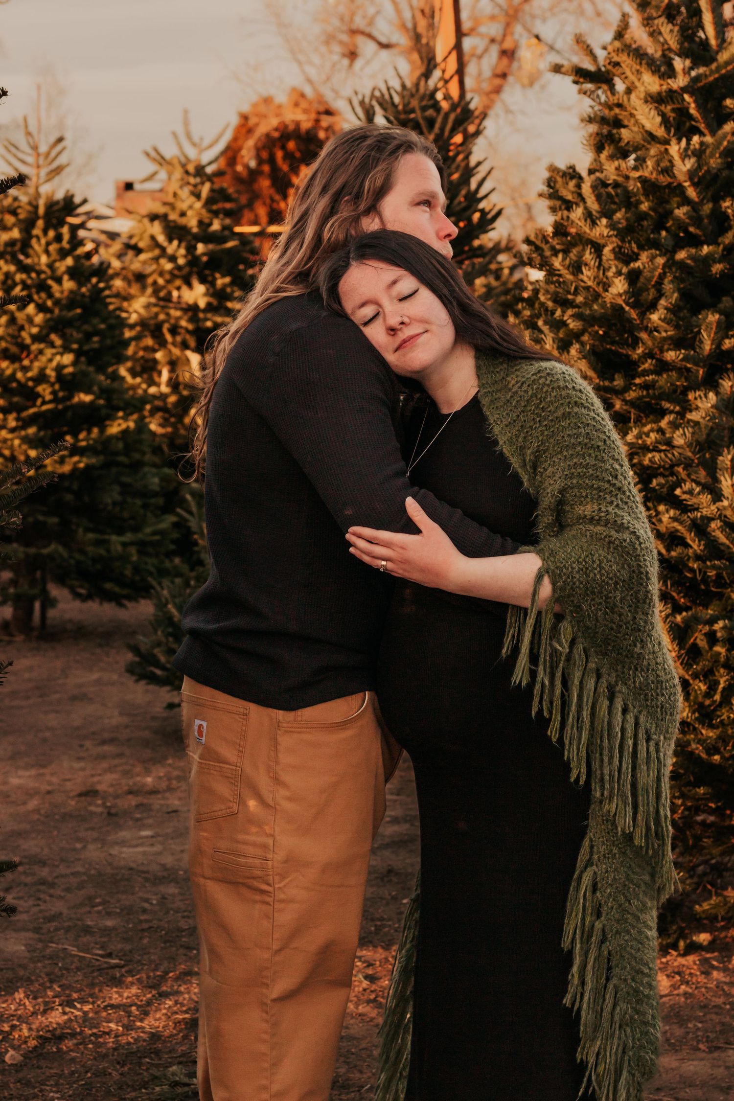 Two people share an intimate embrace at sunset against a backdrop of autumn foliage and golden | Family photographer in Westminster CO