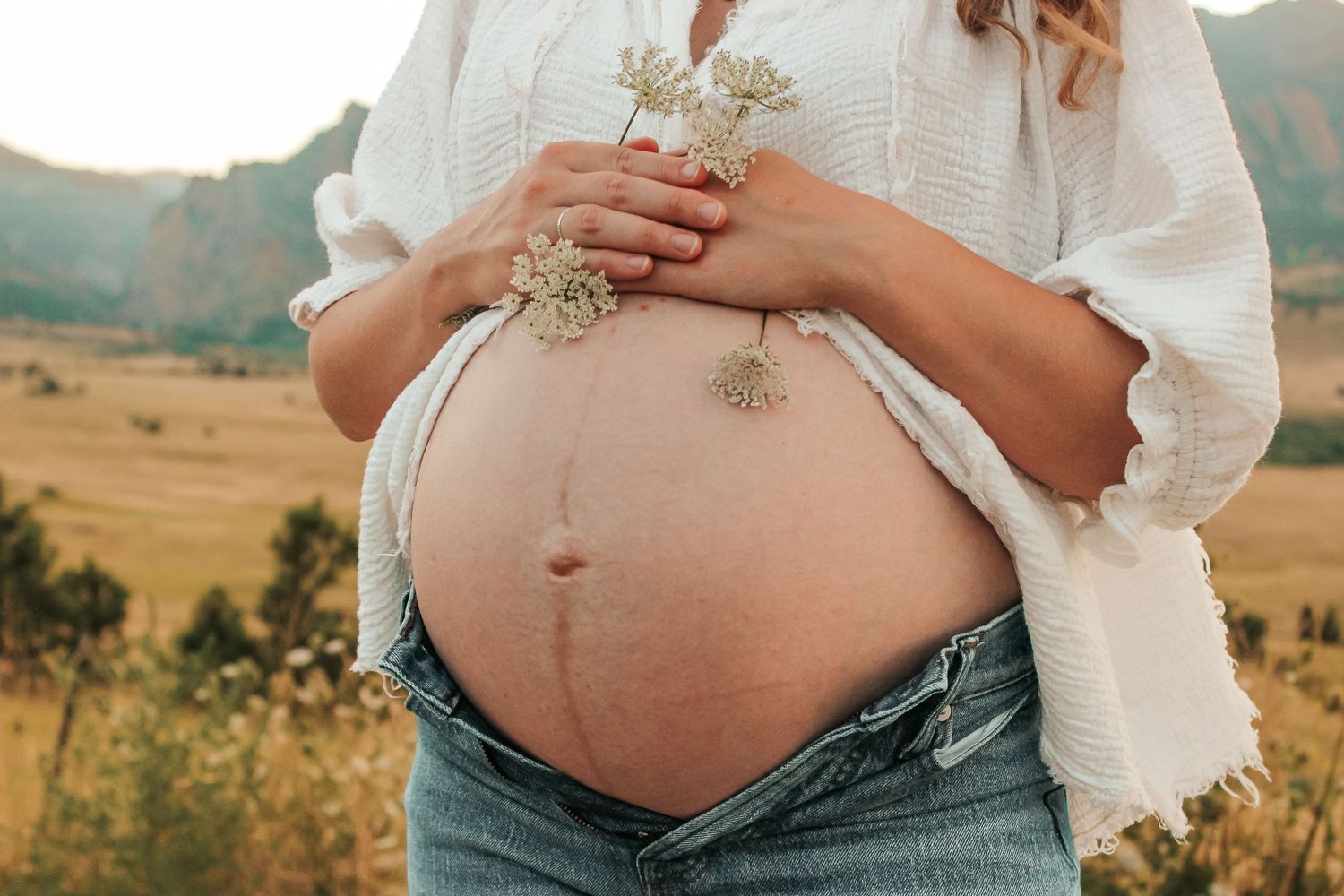 A series of maternity photos showing a pregnant belly in a white dress against a scenic mountain landscape background.