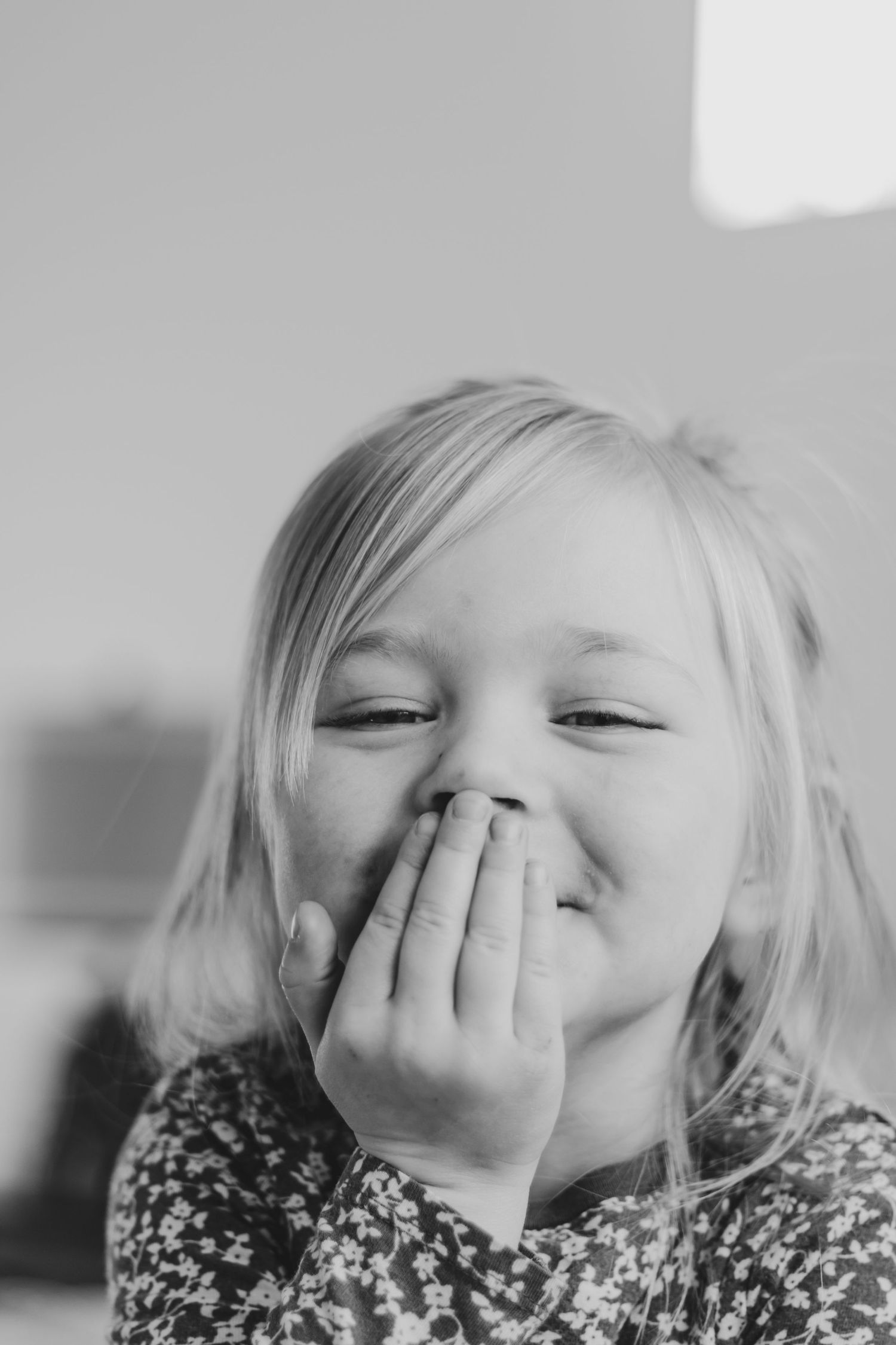 A sequence of black and white photos showing a child giggling and covering their face with their hands.