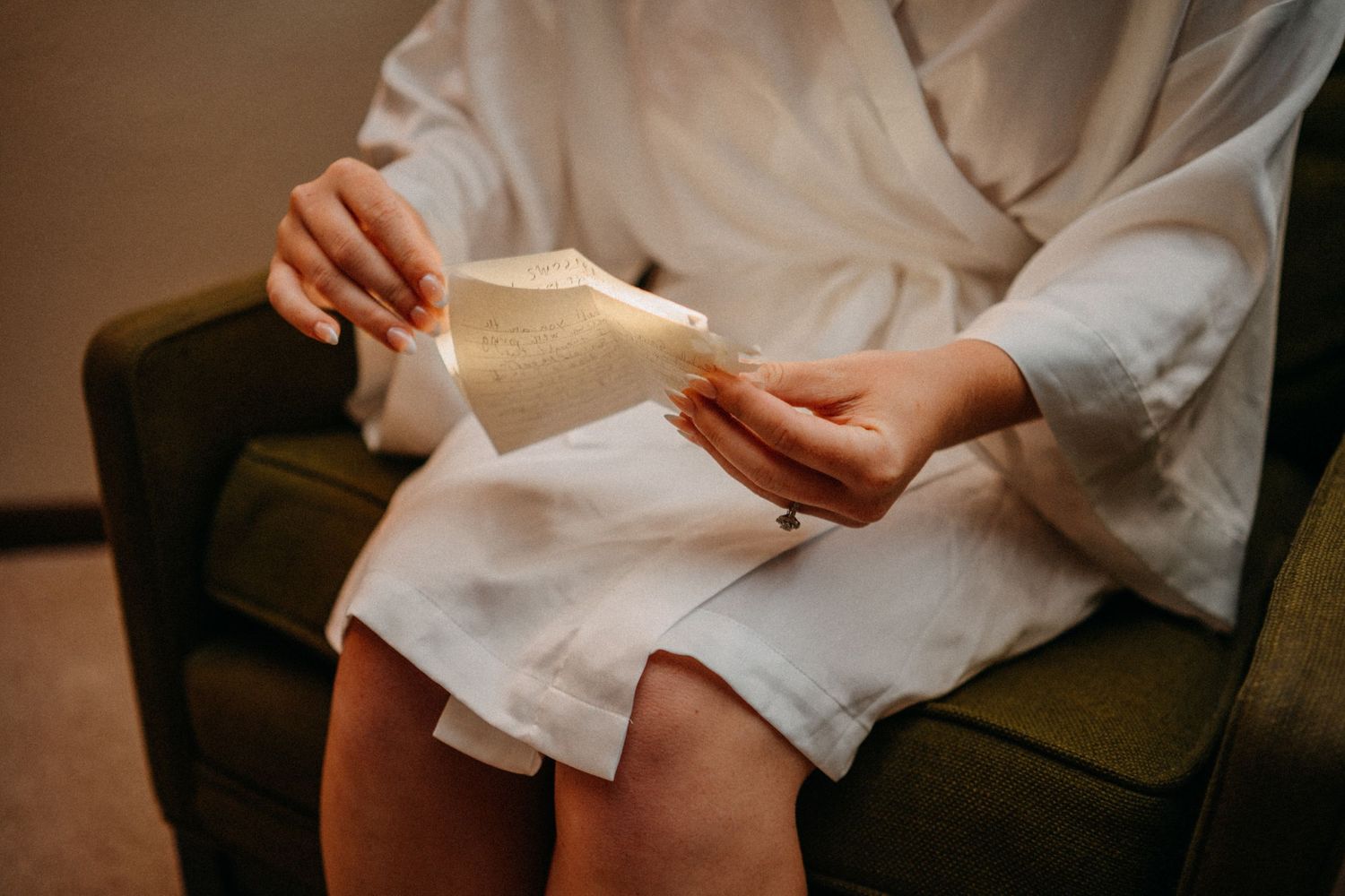 Close-up of hands exchanging wedding rings during an intimate indoor ceremony with soft lighting.