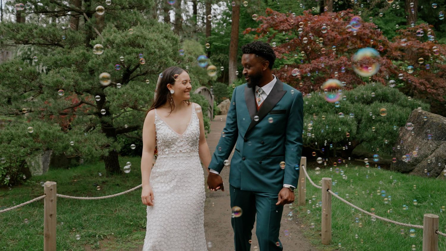 A romantic outdoor wedding ceremony in a lush garden setting with wooden posts and flowing fabric decor.