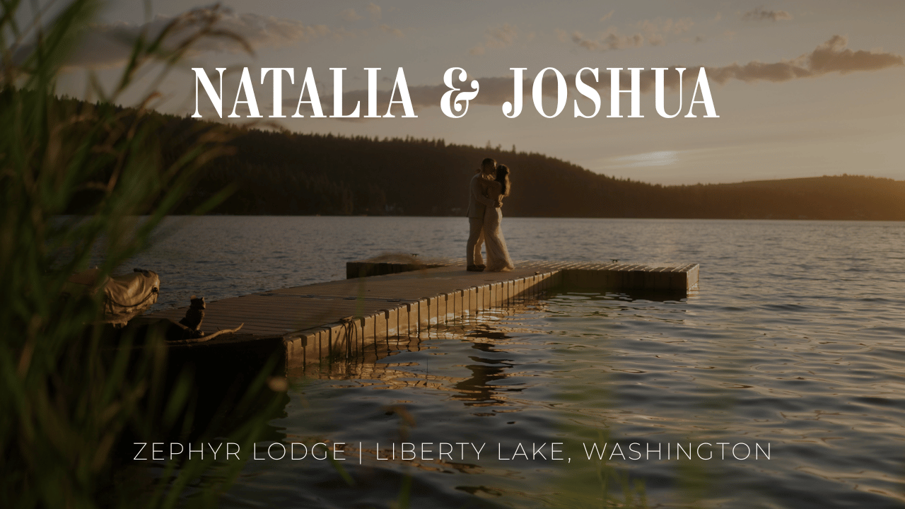 A wooden dock extends over a serene lake at sunset with mountain silhouettes in the background.