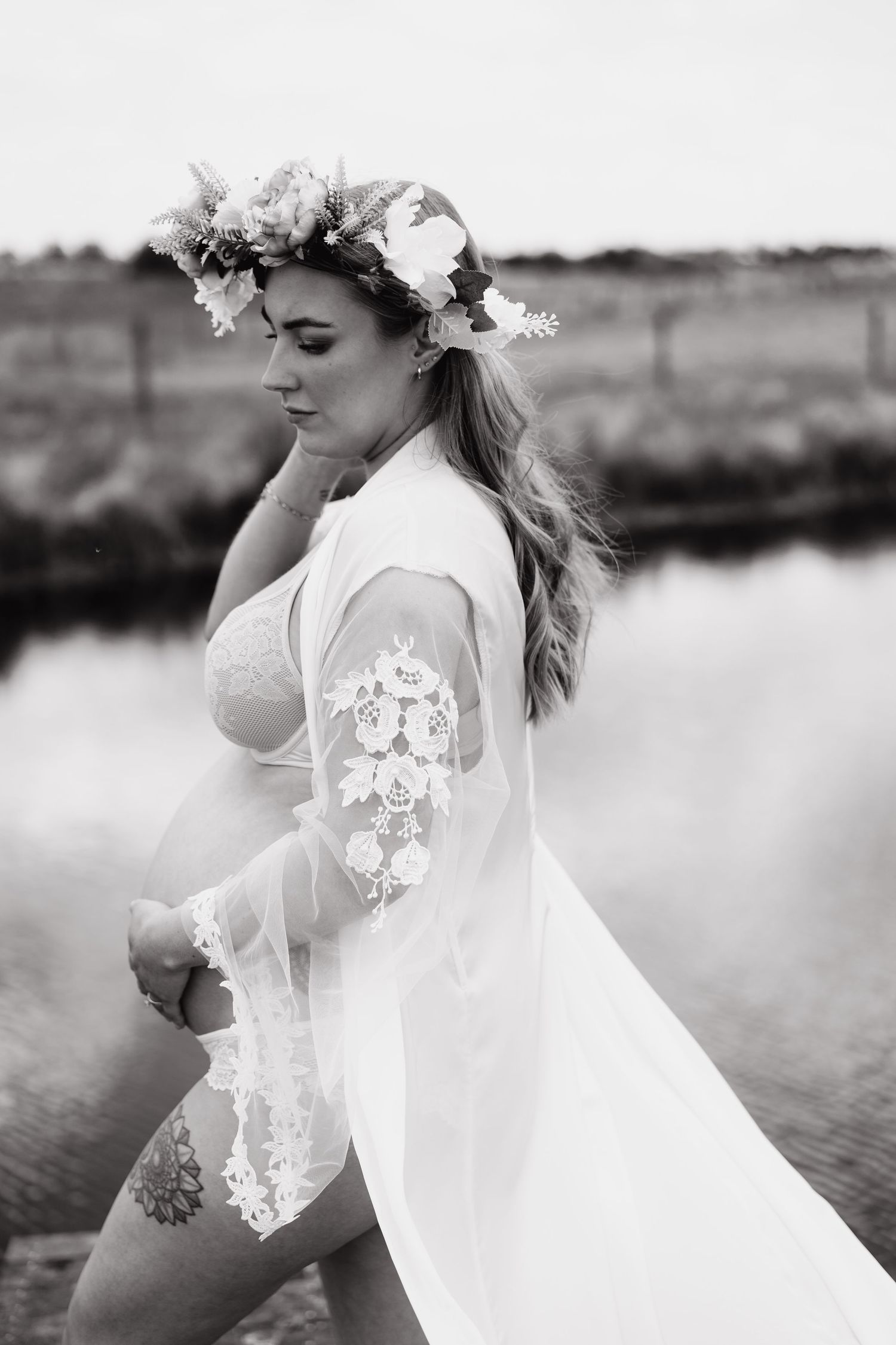 A flowing white dress catches the breeze as someone poses near a waterfront landscape.
