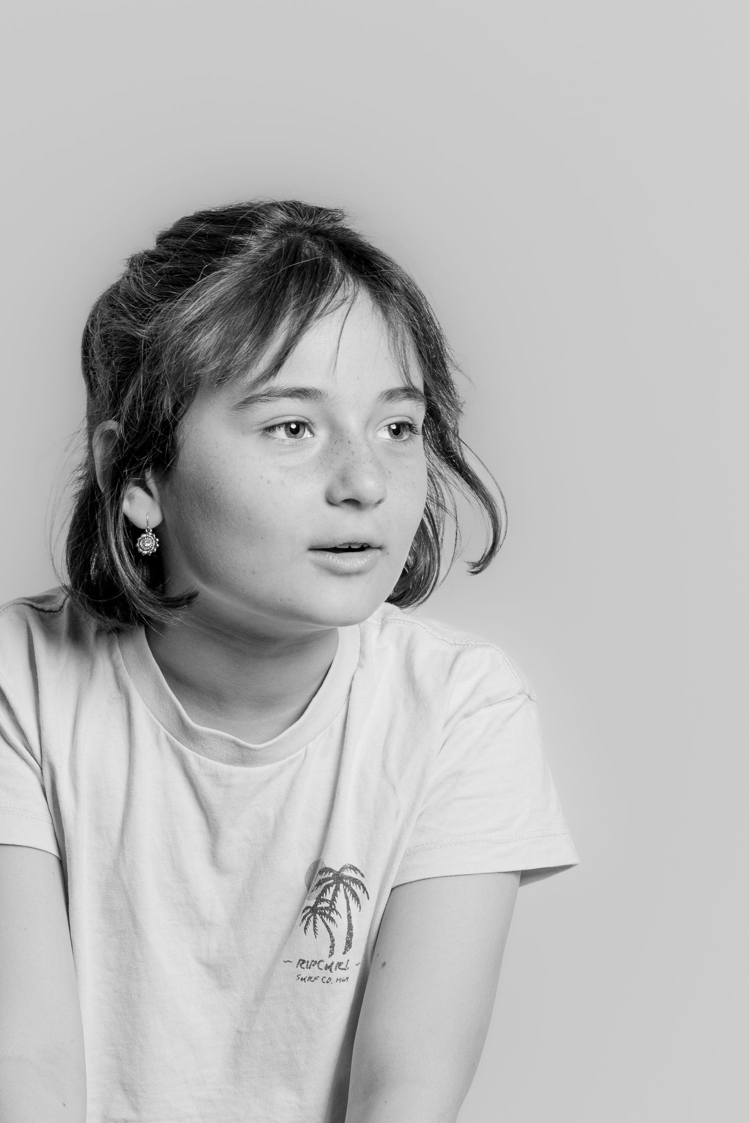 Black and white close-up portrait of a teenage girl in a white t-shirt looking to the side.
