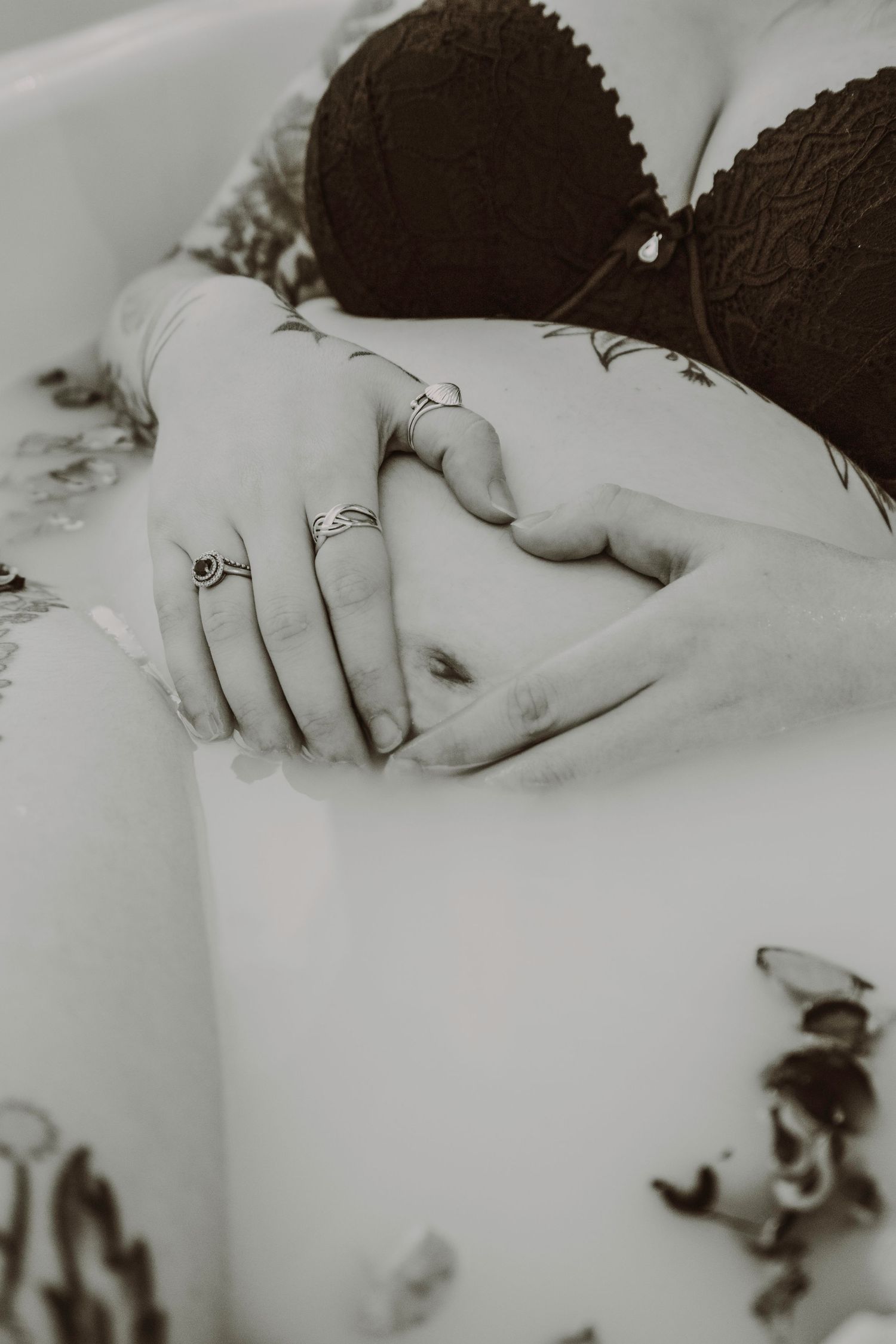 Close-up of a pregnant woman's tattooed hands forming a heart on her baby bump.