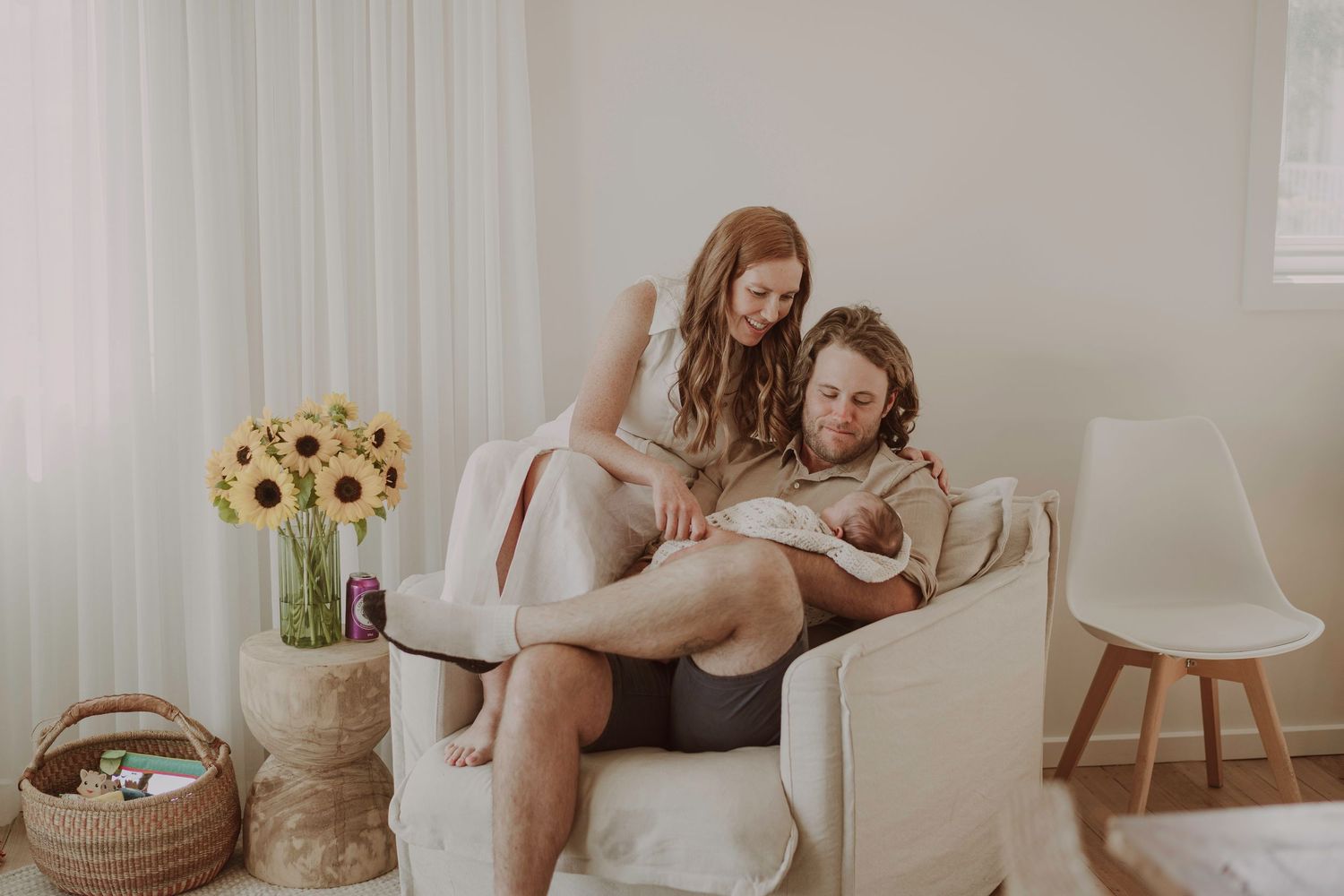 Intimate indoor maternity session with sunflowers and natural window light.