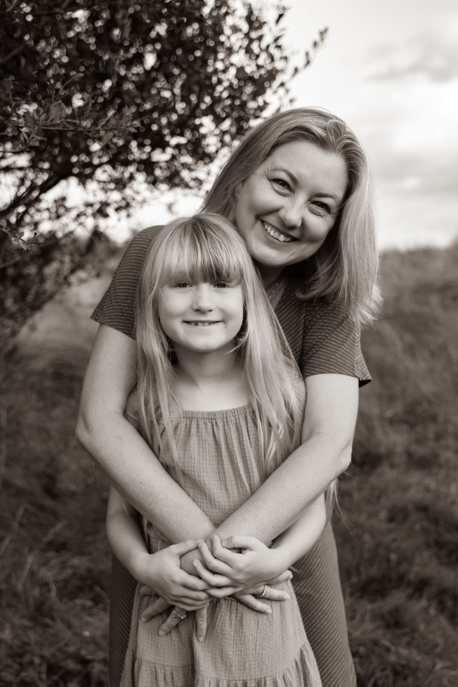 Natural light portrait of family members hugging in outdoor setting.
