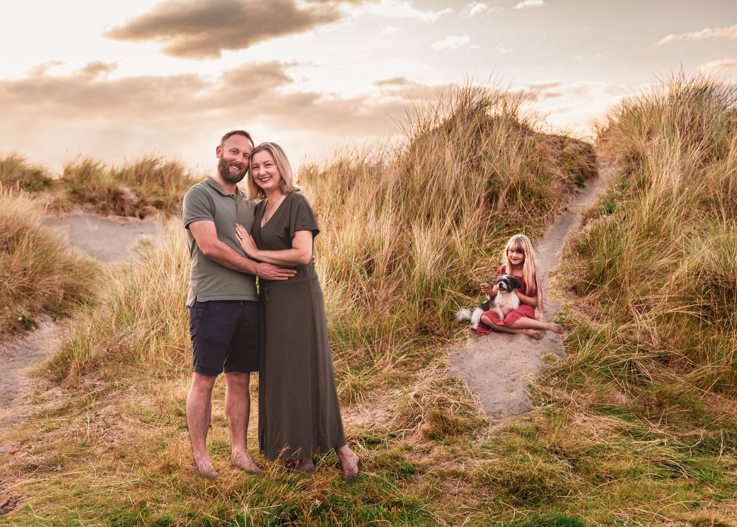 Family exploring coastal dunes together at sunset.