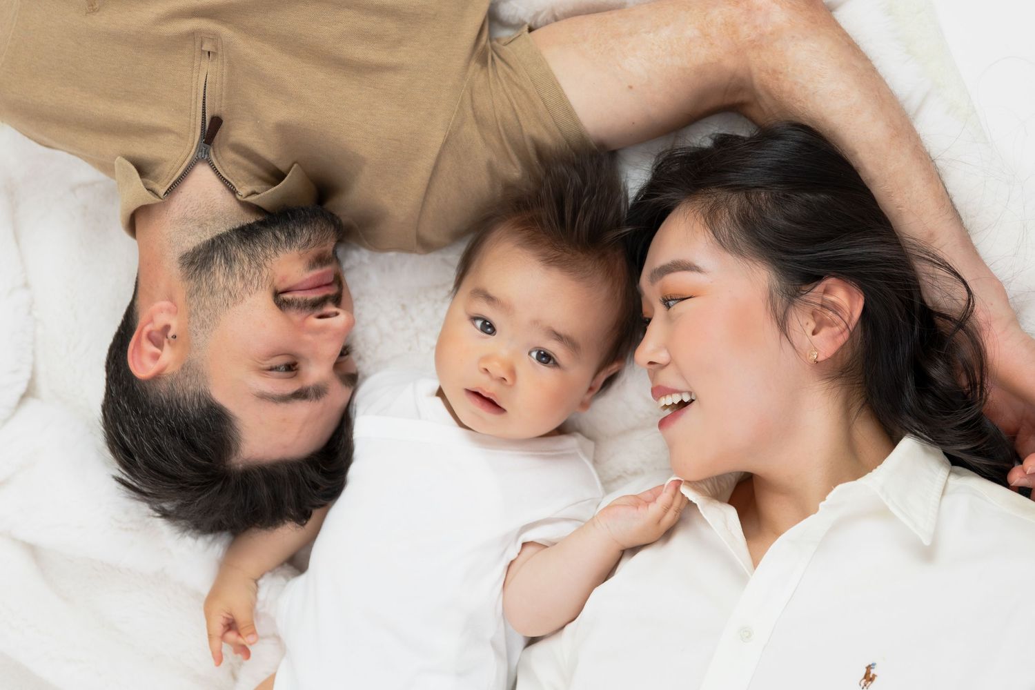 Intimate family moments captured from above on white bedding.