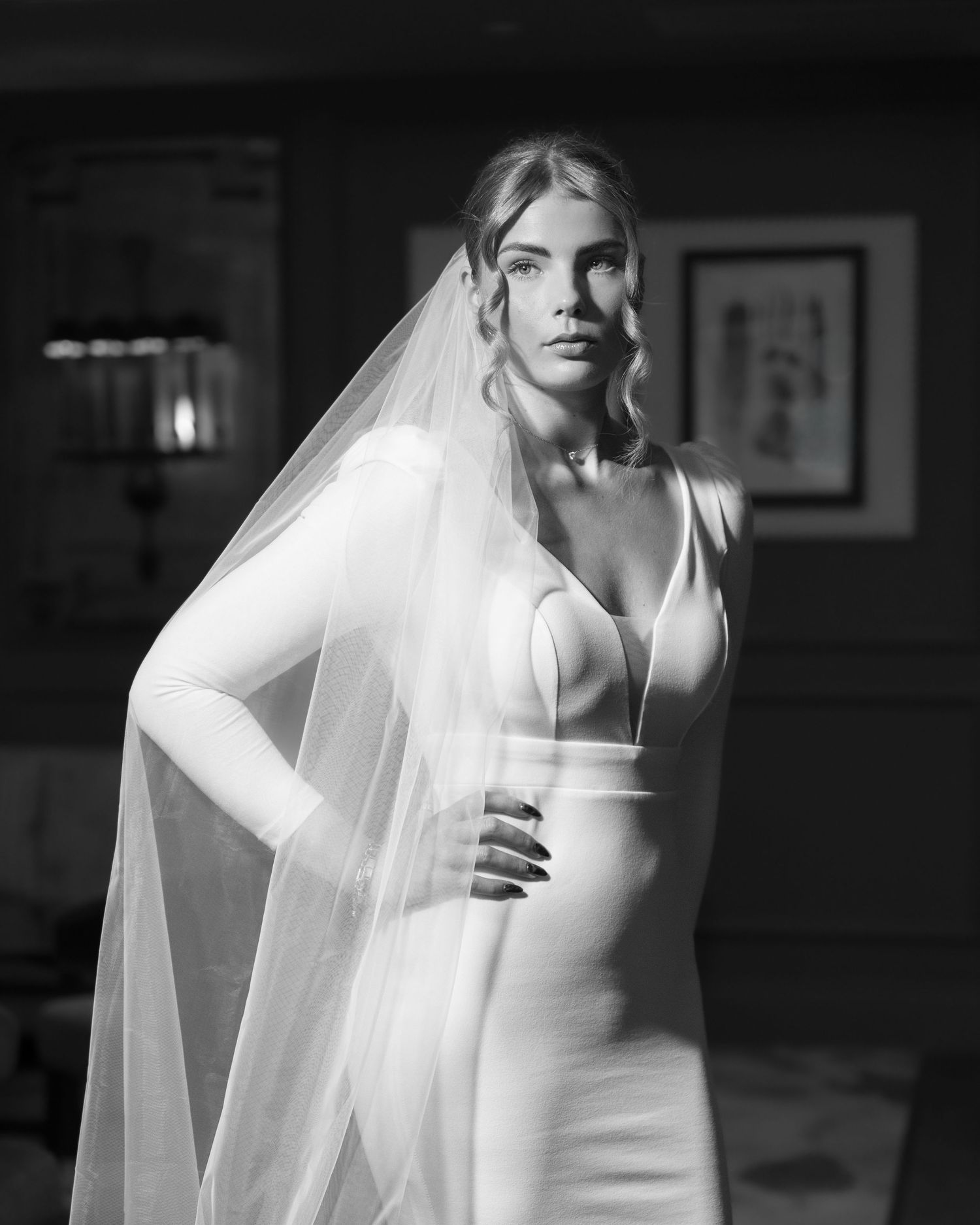 Black and white portrait of a bride in an elegant fitted wedding dress and long flowing veil.