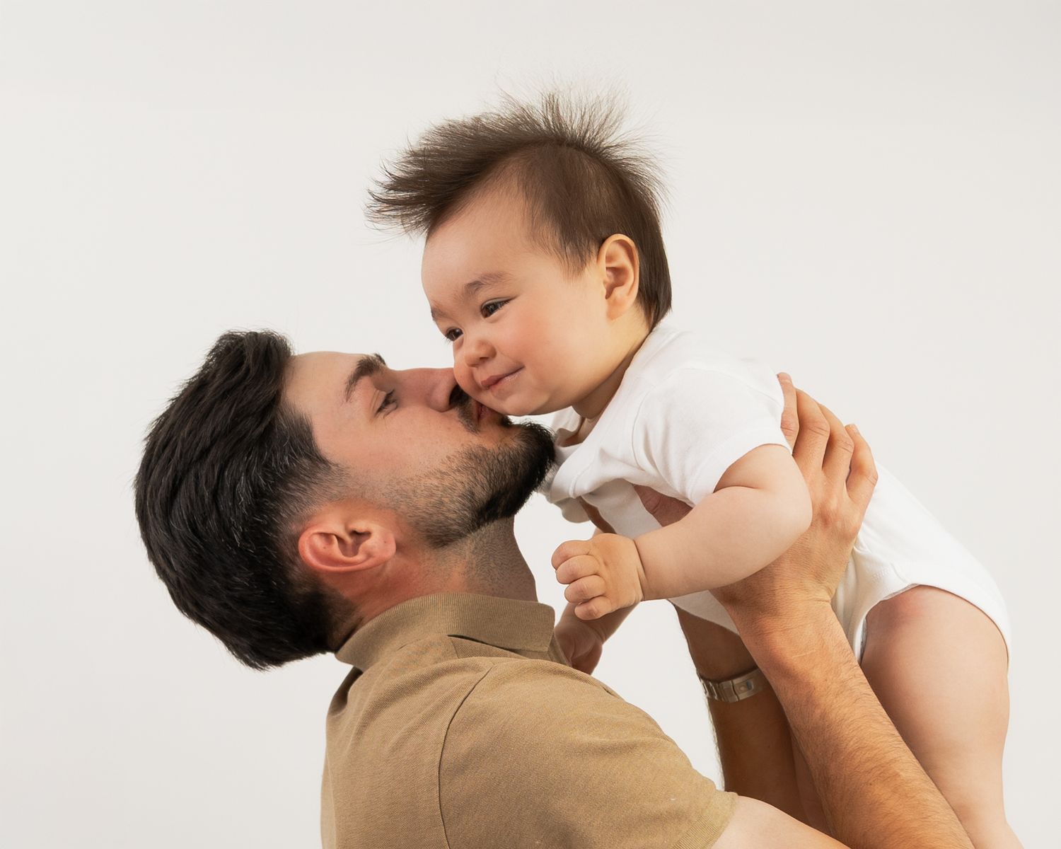A joyful family moment captured against a white background showing playful interaction and laughter.
